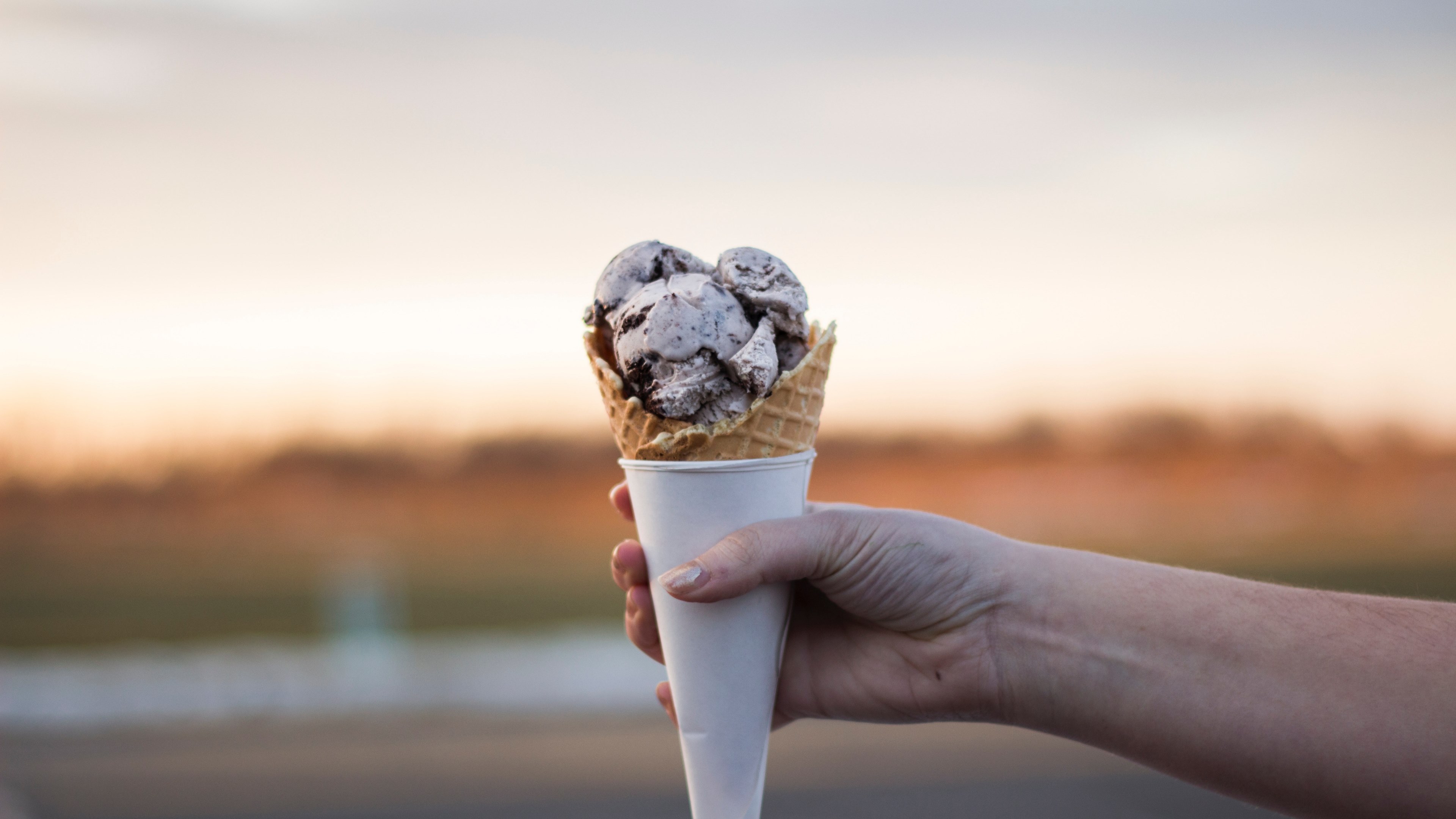 Wallpaper / hand holding scoops of sweet ice cream in a cone, ice cream dessert 4k wallpaper free download