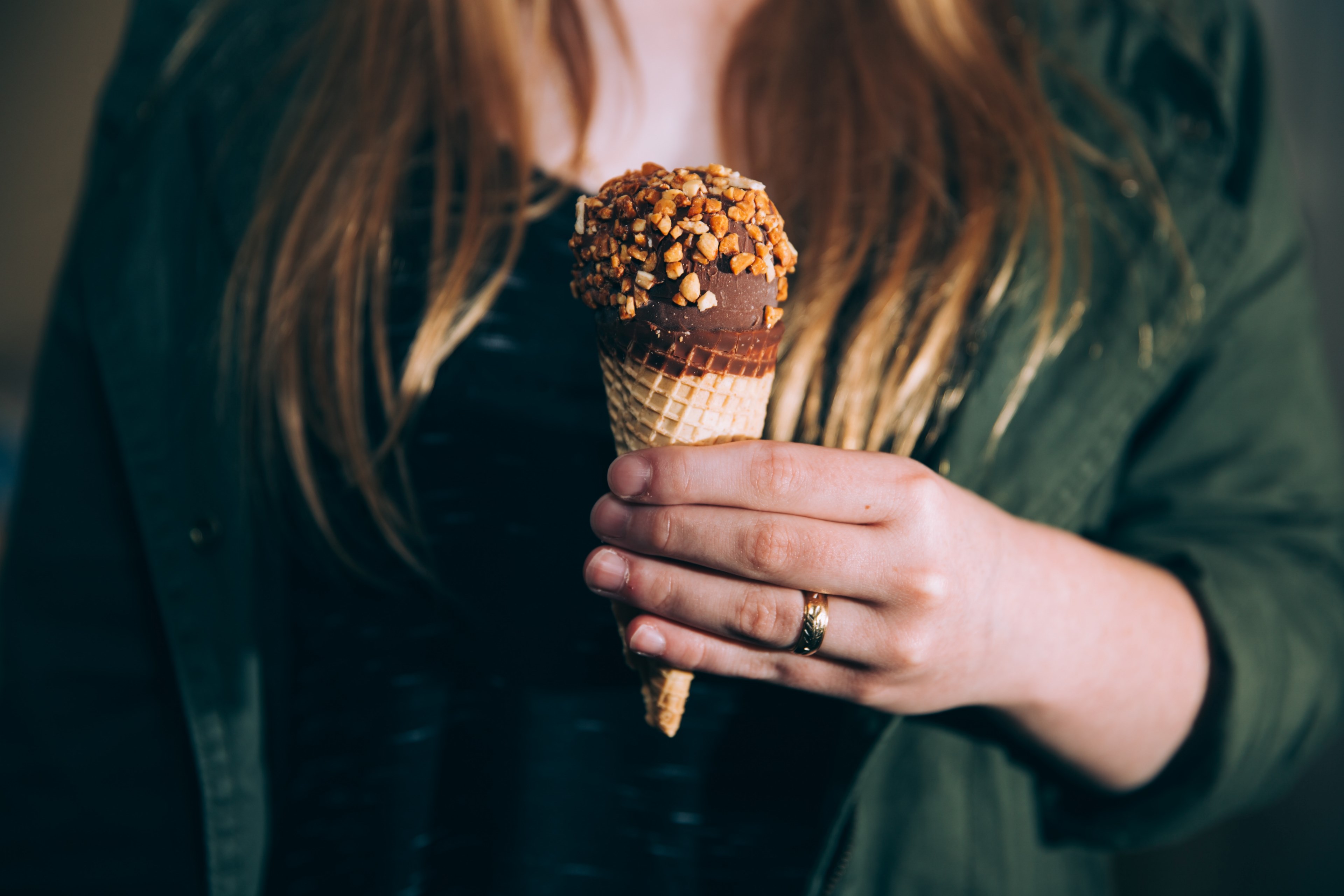 Wallpaper / a woman holding a chocolate ice cream cone sprinkled with nuts, indulgent sweet treat 4k wallpaper free download