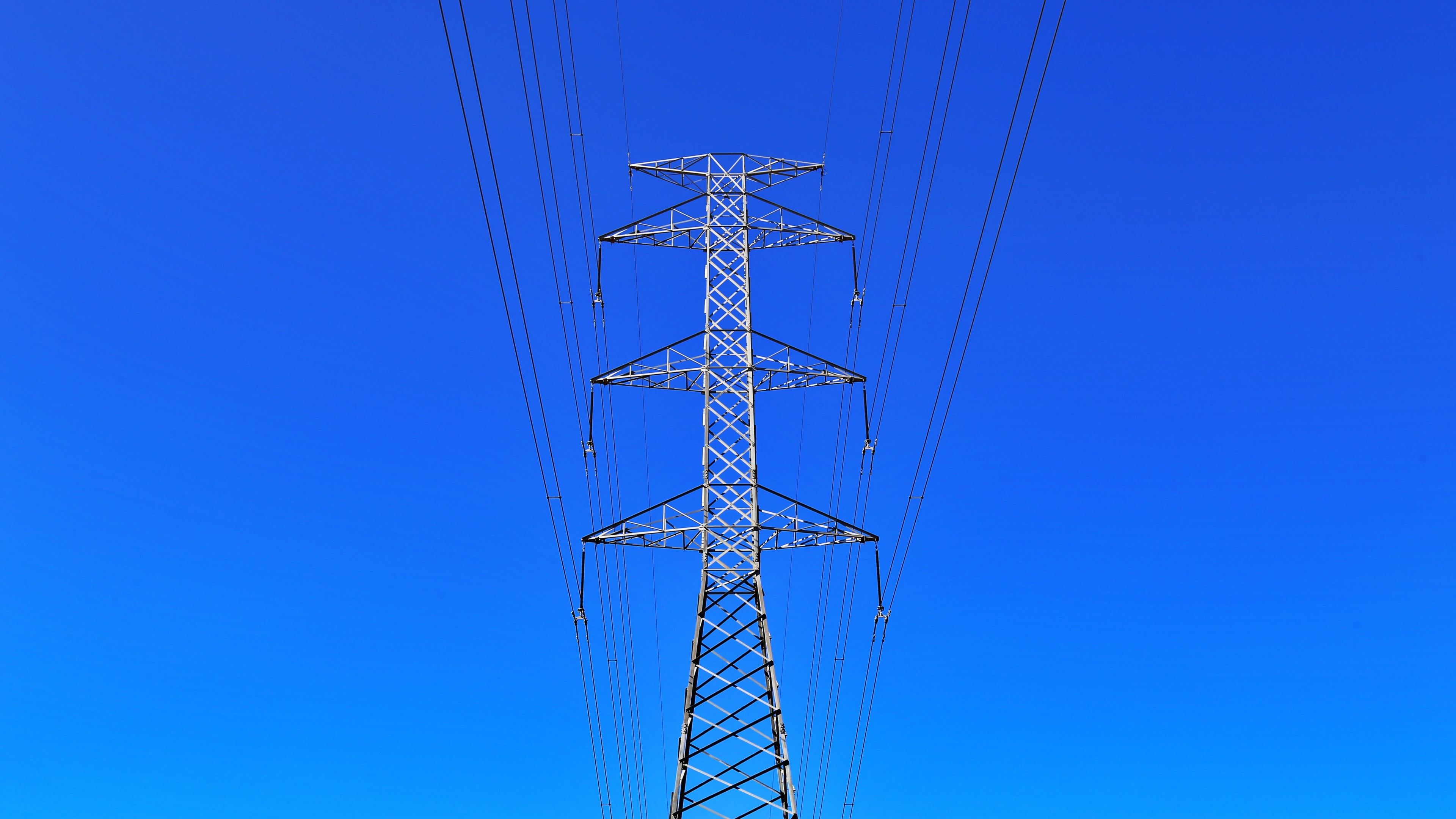 Wallpaper / electric tower with power lines creates symmetrical views on a clear blue sky, electrical wires 4k wallpaper free download