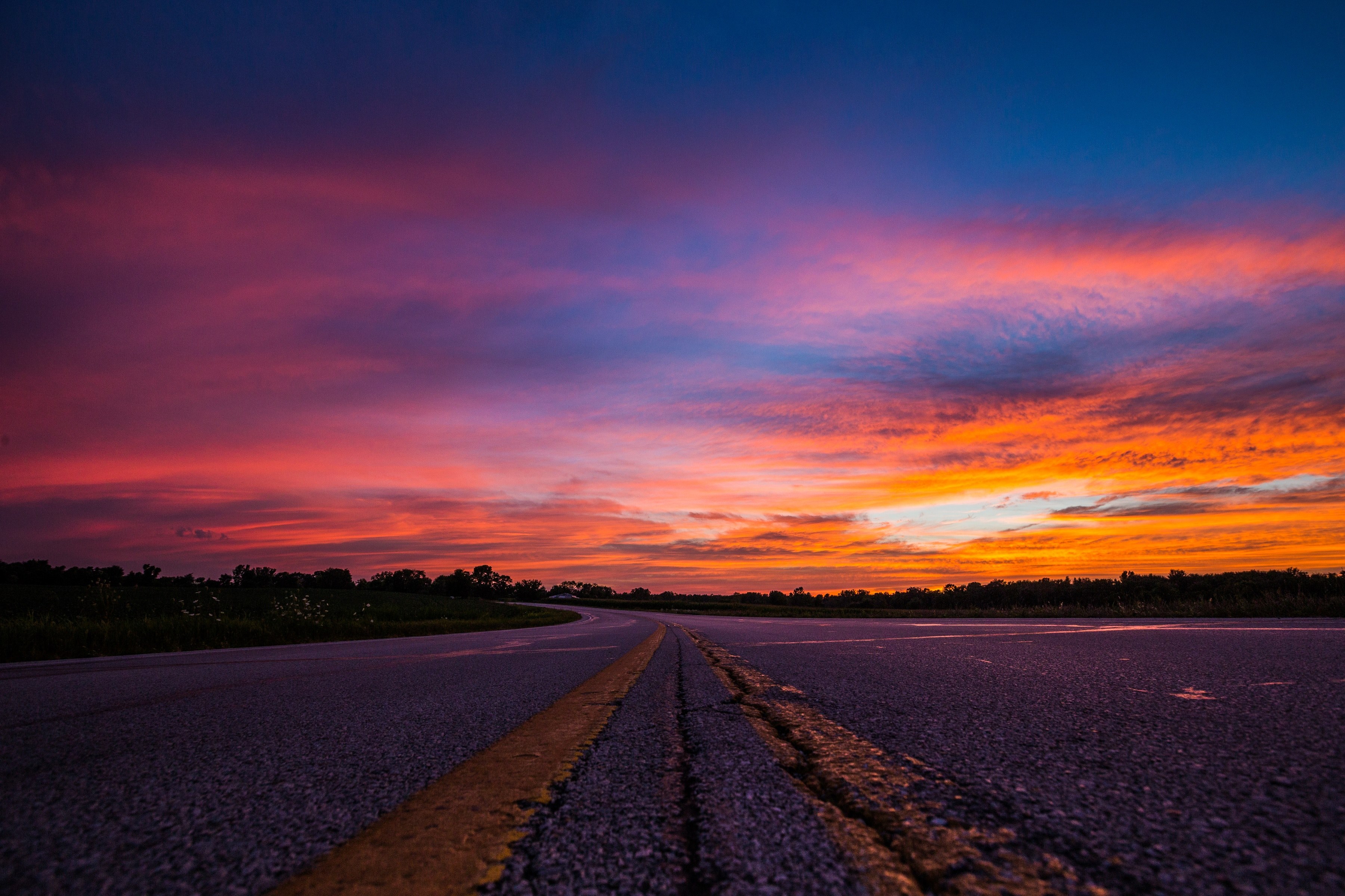 Wallpaper / a pink orange and blue sunset glow upon the asphalt of a highway road, cool sunset hues on a highway 4k wallpaper free download