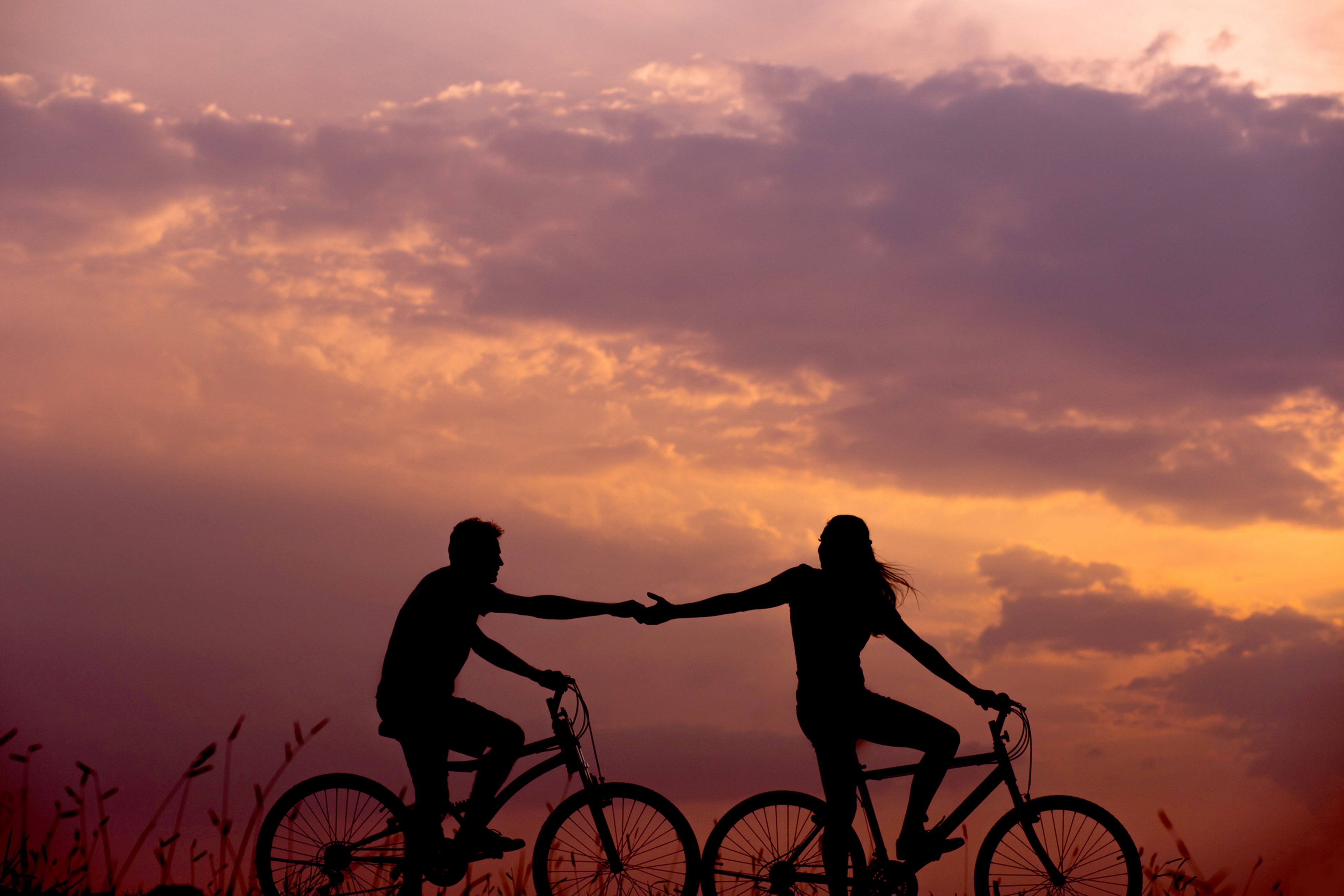Wallpaper / lovers share a silhouetted bicycle ride hands reaching out to each other, dont let go 4k wallpaper free download