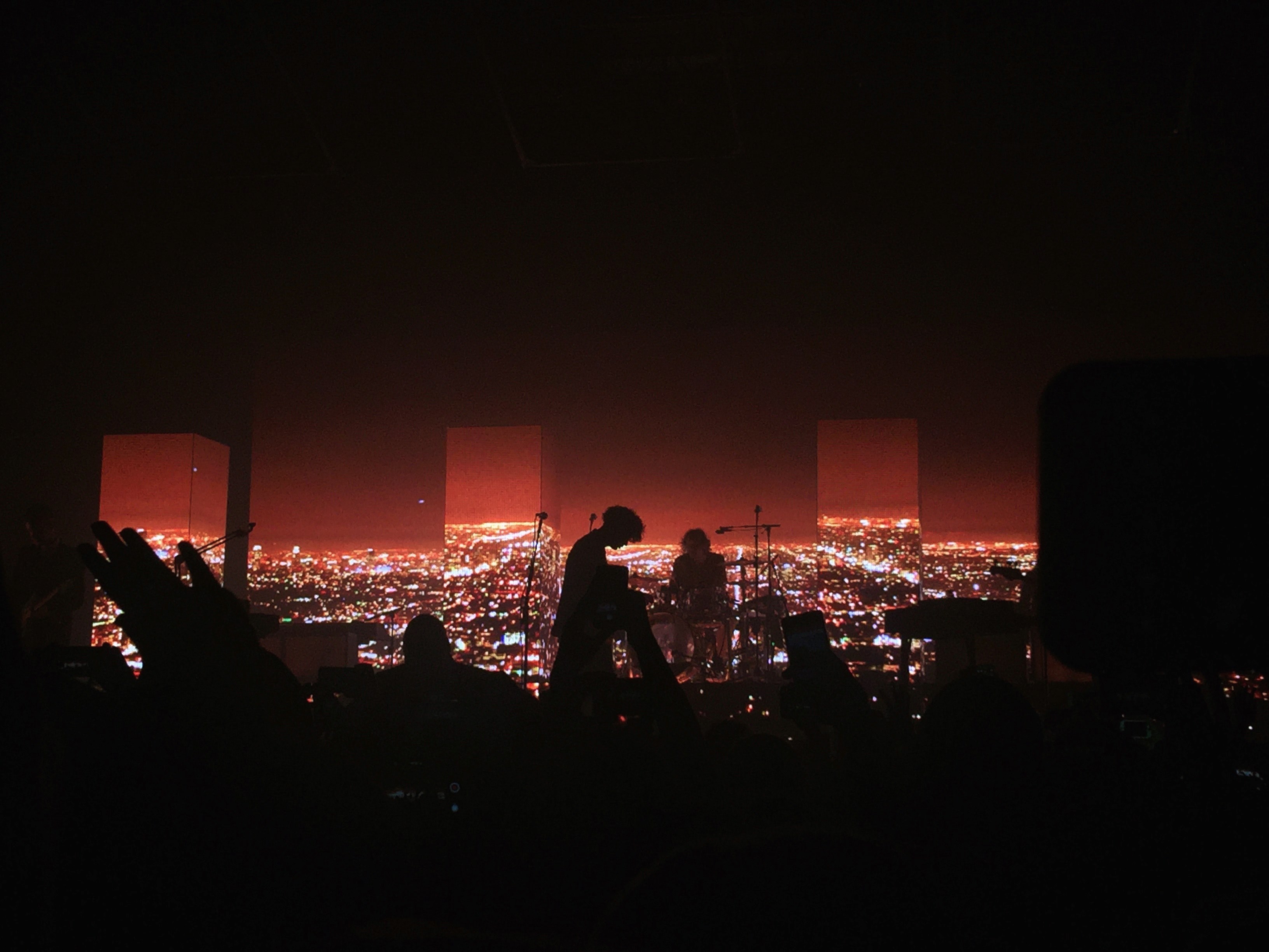 Wallpaper / dark concert venue with silhouetted audience and band in front of red cityscape, the 1975 4k wallpaper free download