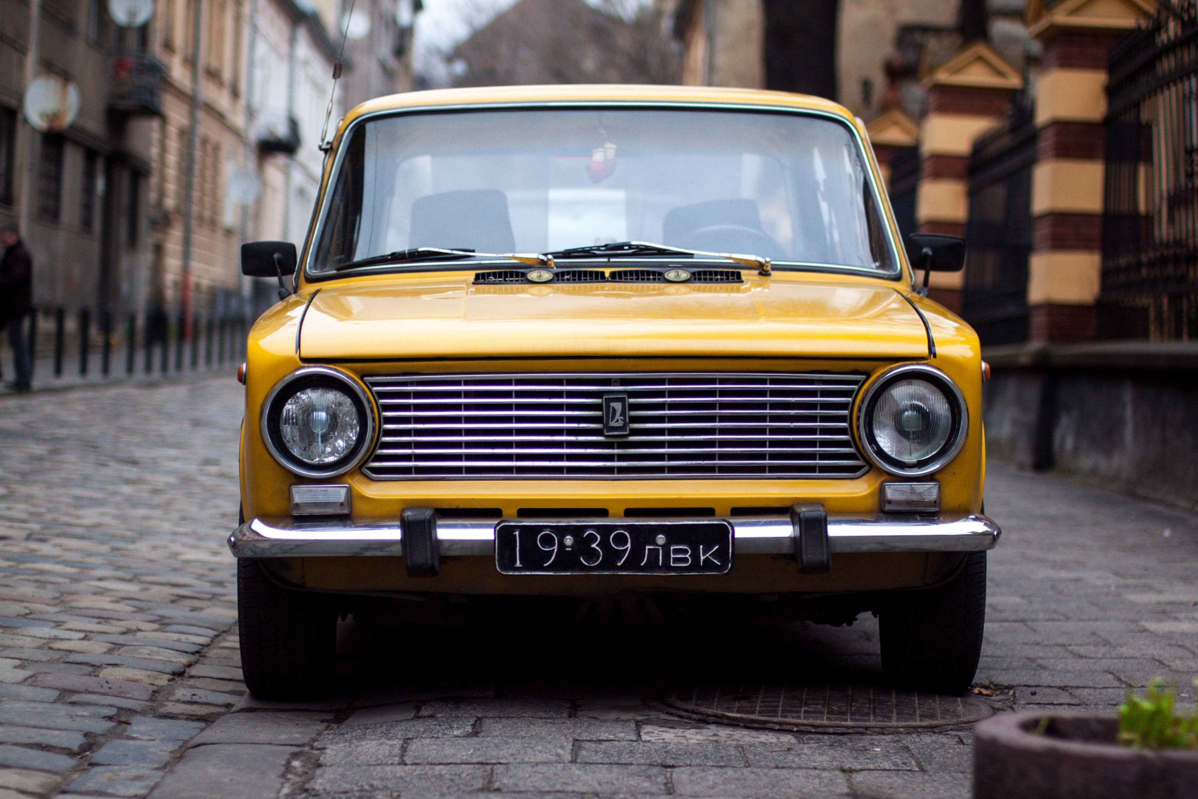 Wallpaper / an old vintage yellow car parked on a cobblestone street, yellow vintage car 4k wallpaper free download