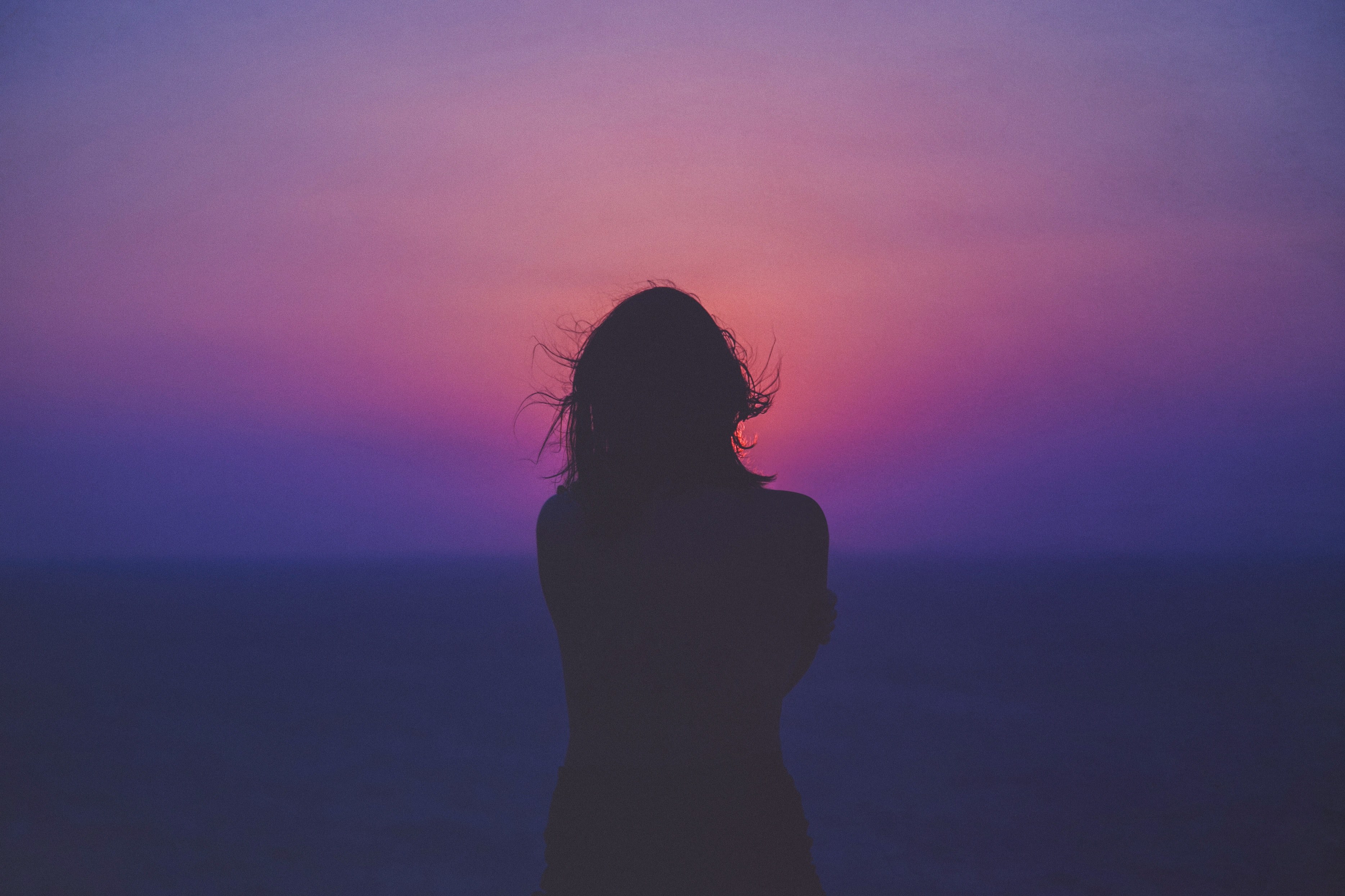 Wallpaper / silhouette of a woman against a pink and purple sunset hair floating in the wind, lost in the sunset 4k wallpaper free download