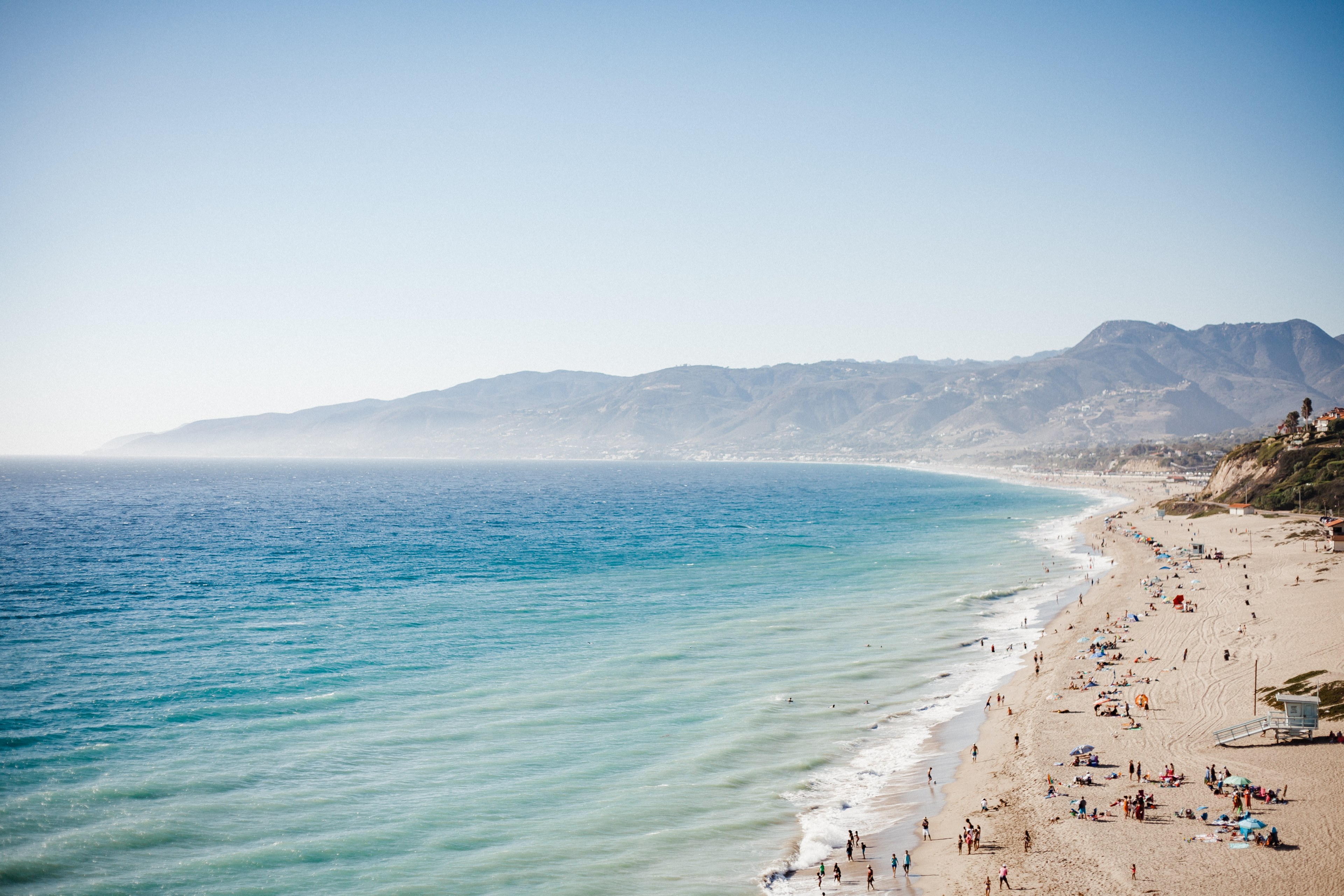 Wallpaper / clean ocean washing up on sand shore filled with people in malibu, malibu ca 4k wallpaper free download