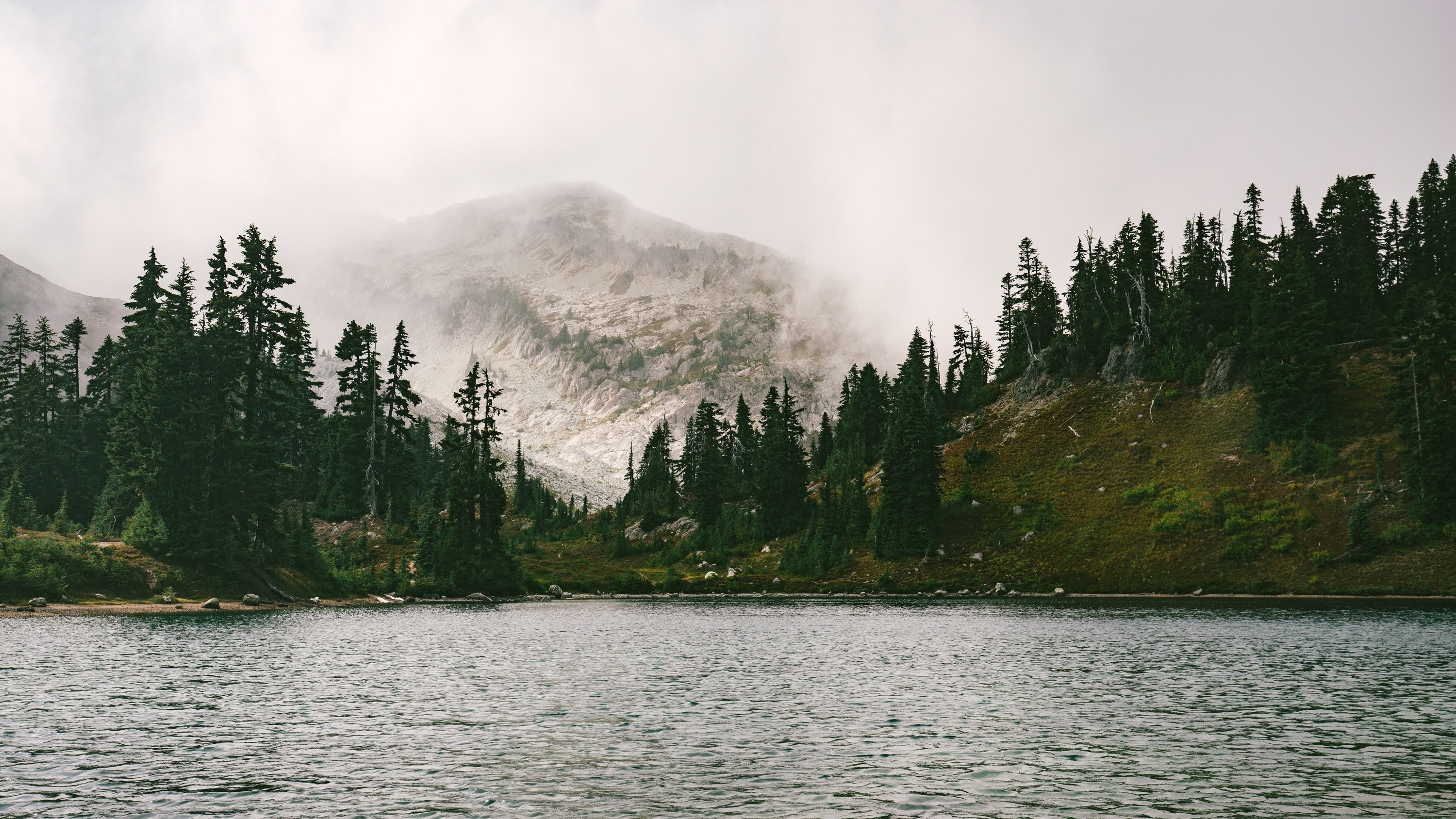 Wallpaper / a foggy mountain near a lake in north cascades national park, misty mountain by a lake 4k wallpaper free download