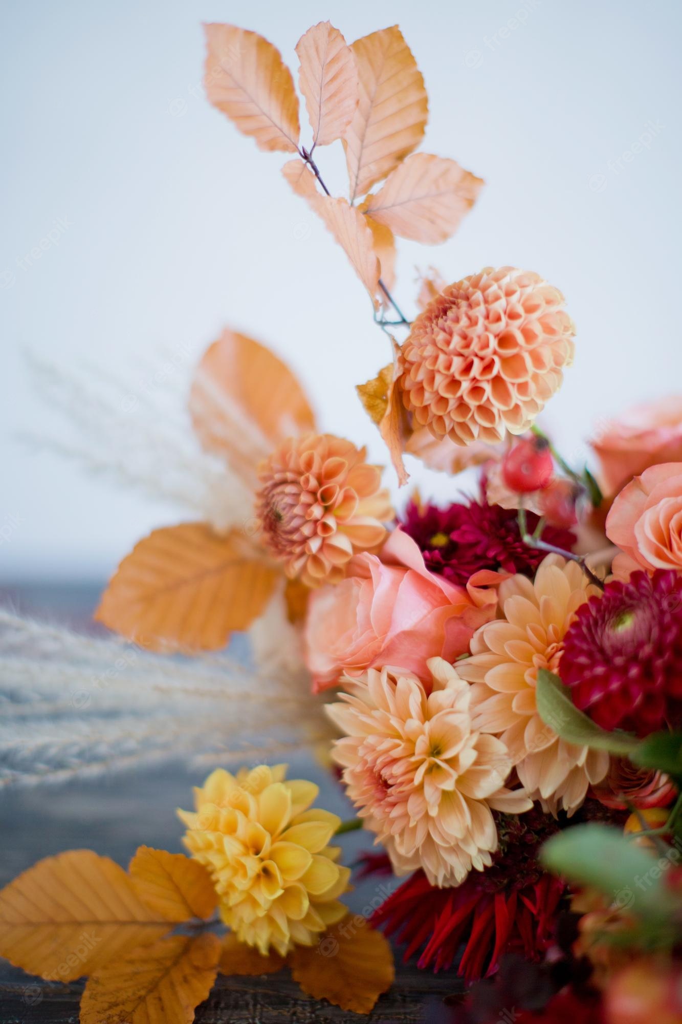 Premium Photo. Beautiful autumn bouquet with orange and red flowers and berries autumn bouquet with ribbons on a wooden table