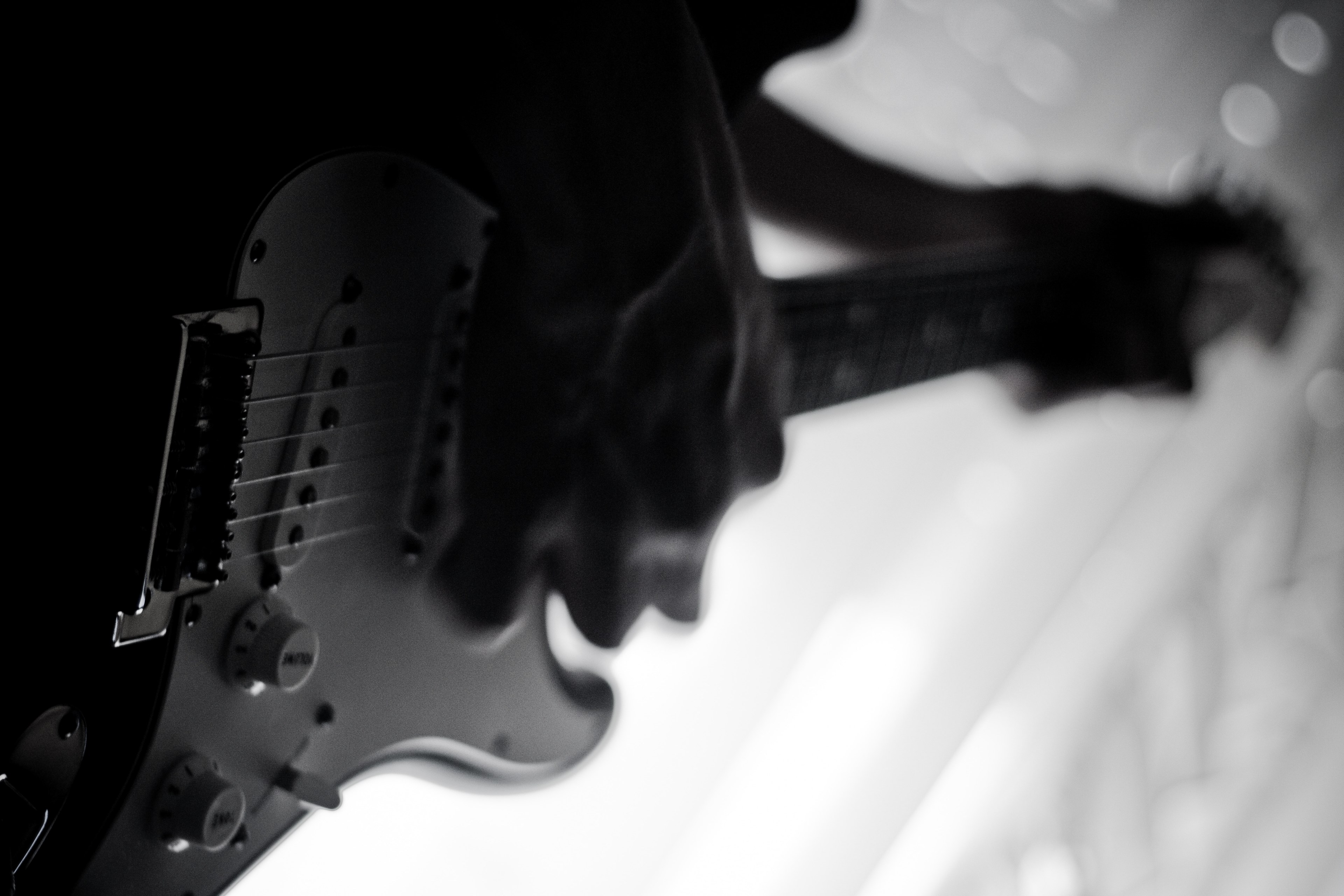 Wallpaper / a low angle black and white shot of a person playing an electric guitar, guitarist in black and white 4k wallpaper free download