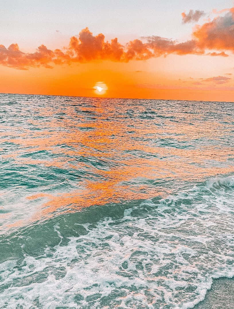 Download A Sunset Over The Ocean With Waves