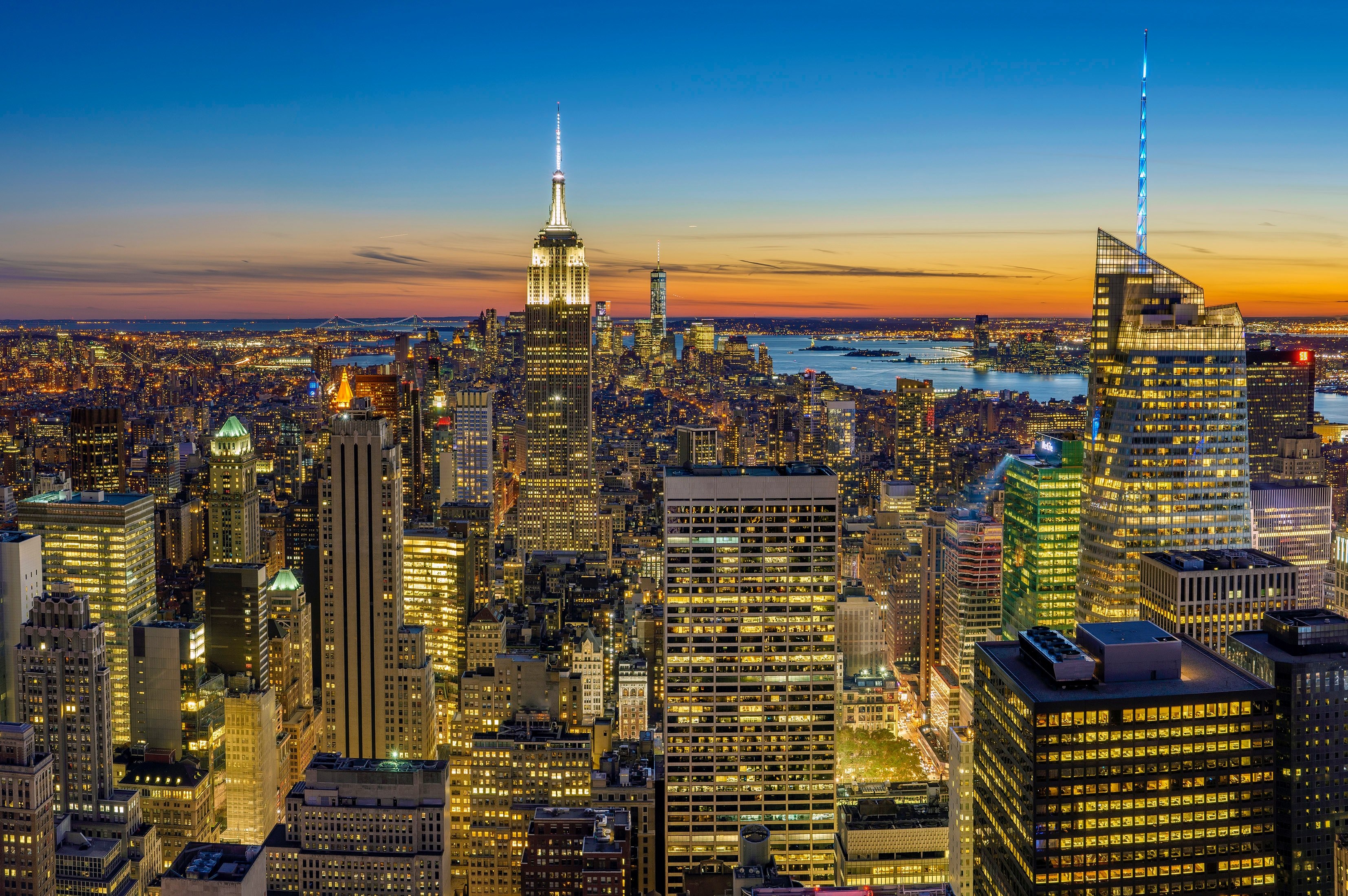 Wallpaper / new york city skyline with skyscrapers lit up while sun sets, new york lights 4k wallpaper free download