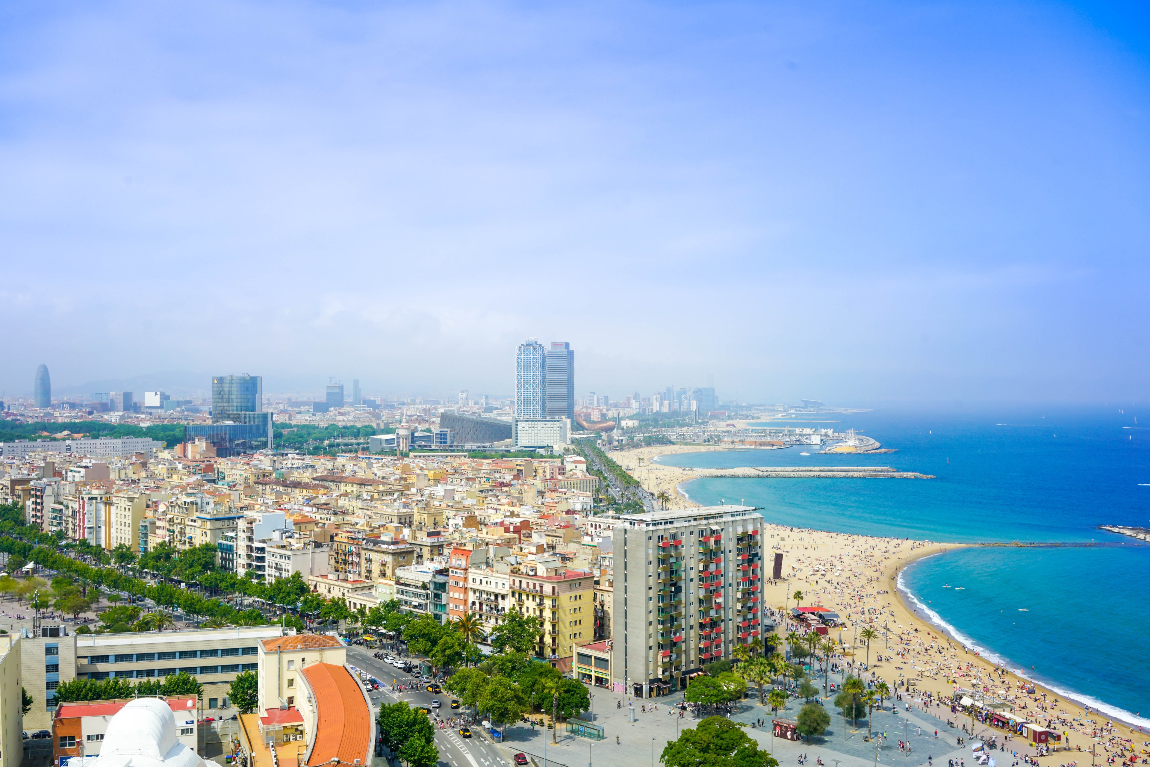 Wallpaper / beautiful cityscape summer view of high rise around beach in barcelona just around the blue ocean, cityscape of barcelona city beach 4k wallpaper free download