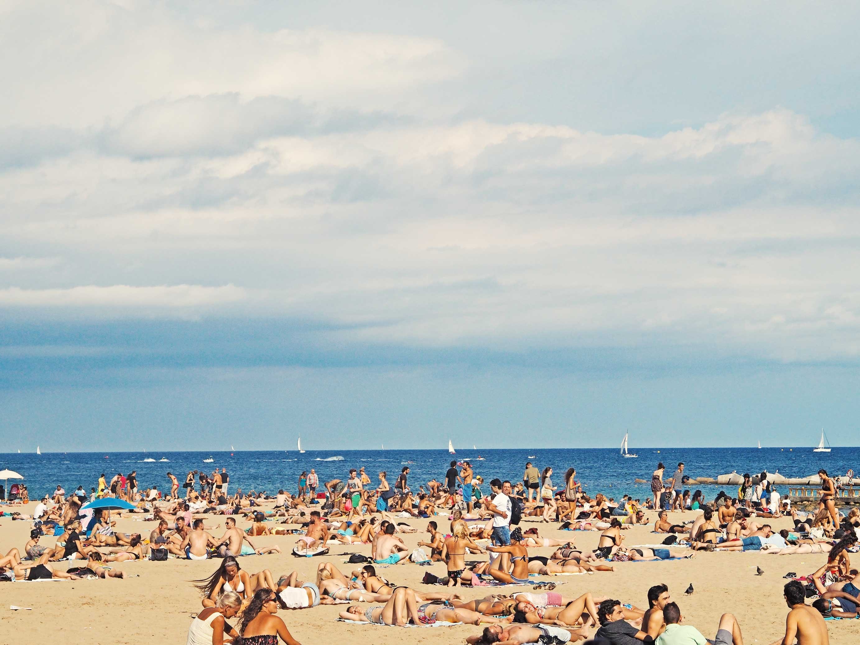 Wallpaper / beach is crowded with people on tourism enjoying the summer holiday and vacation in barcelona, crowded barcelona beach 4k wallpaper free download