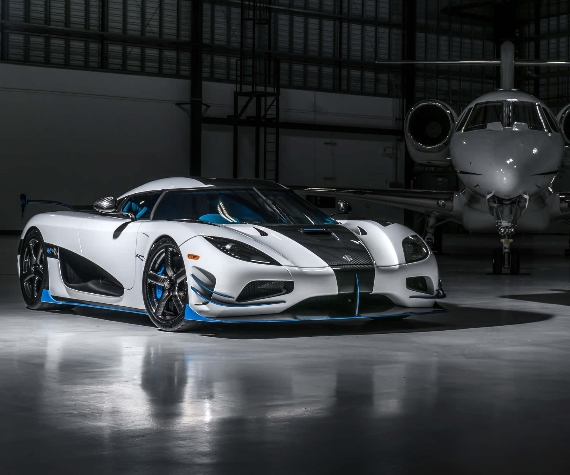 Download A White And Blue Sports Car Is Parked In Front Of A Plane Wallpaper