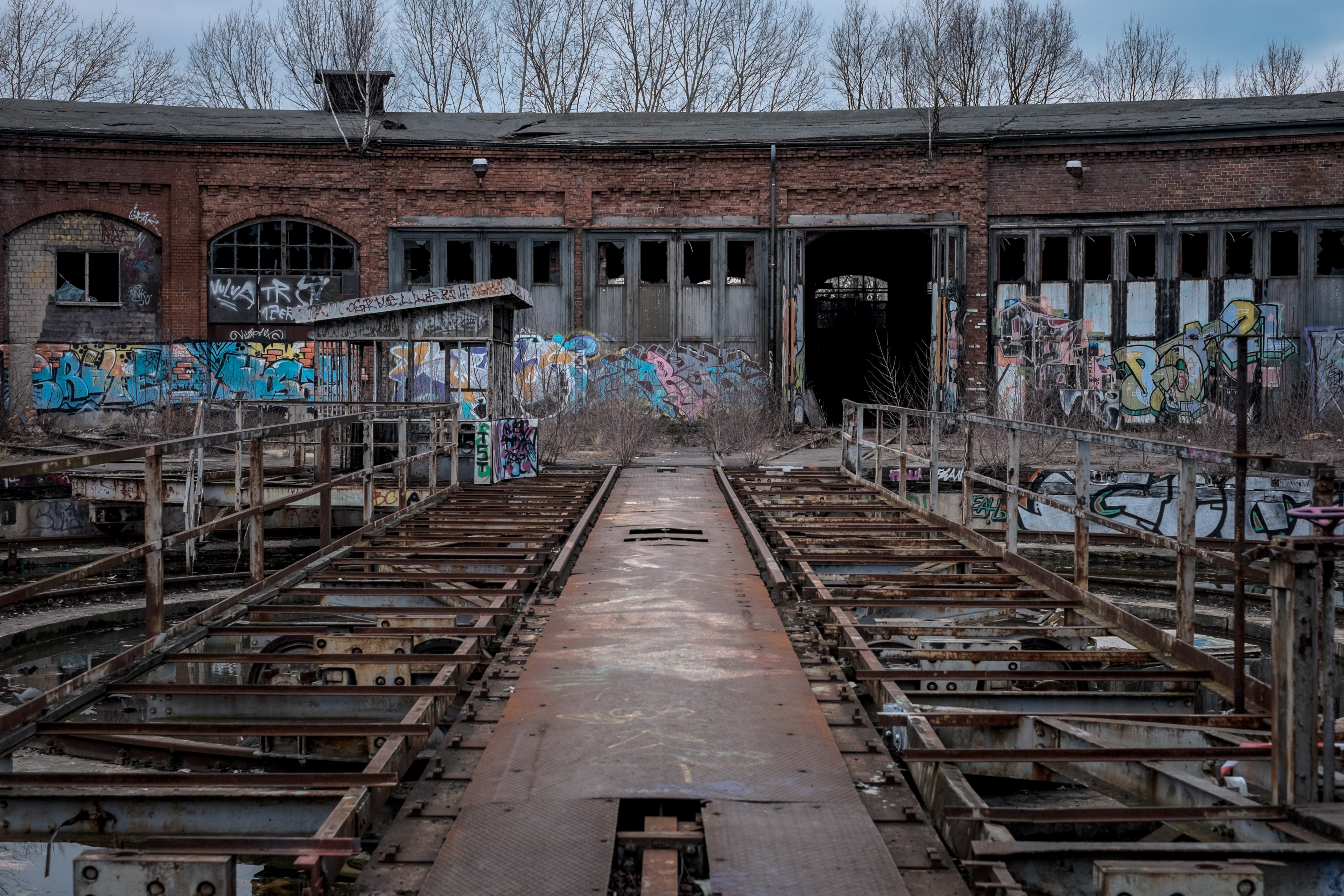 Wallpaper / old decaying urban building with graffitied walls and rusted metal railings with large doors in the background, abandoned city buildings 4k wallpaper free download