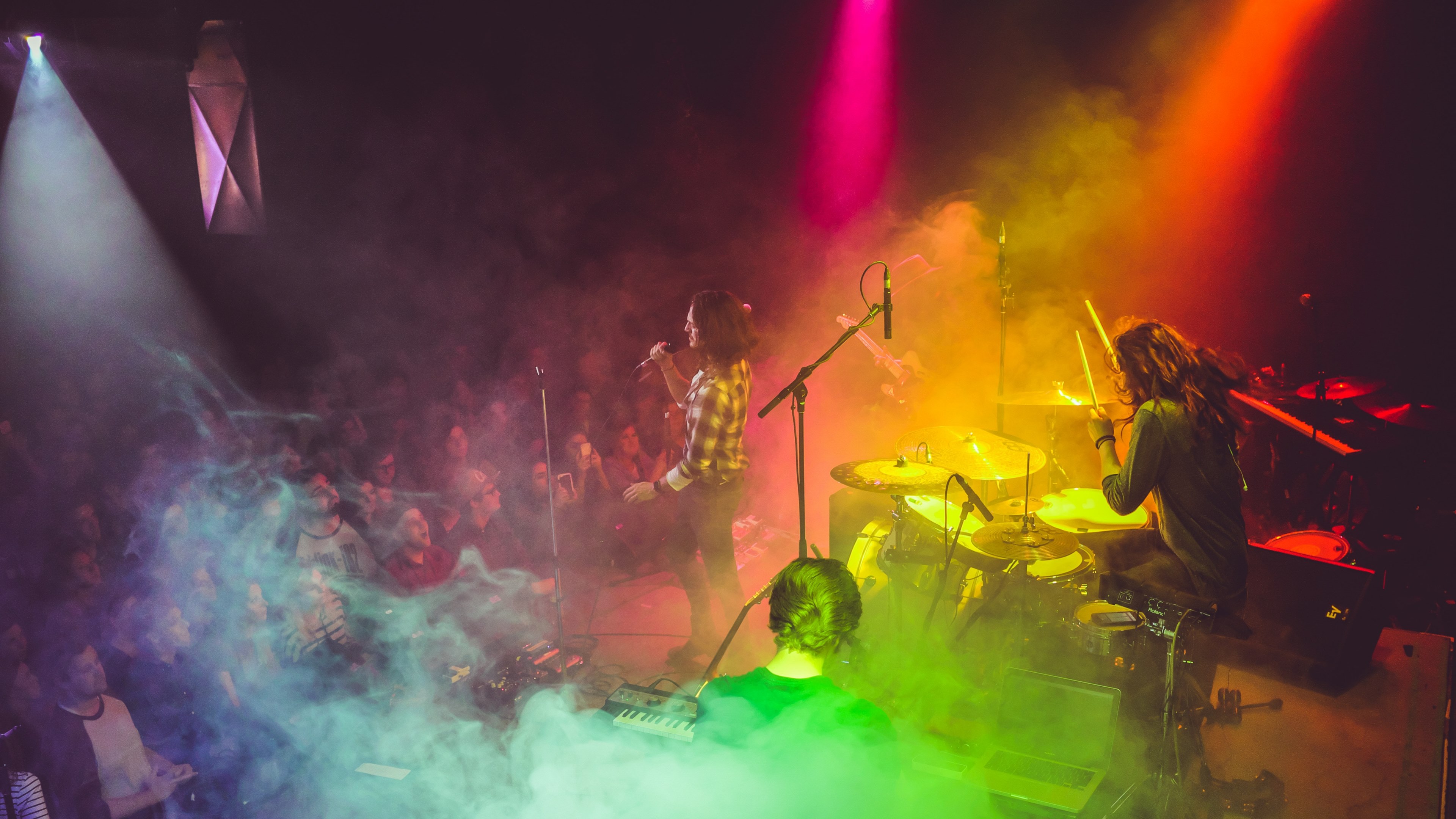 Wallpaper / a band performing on stage with rainbow colored lights flooding them from above, band in rainbow smoke 4k wallpaper free download