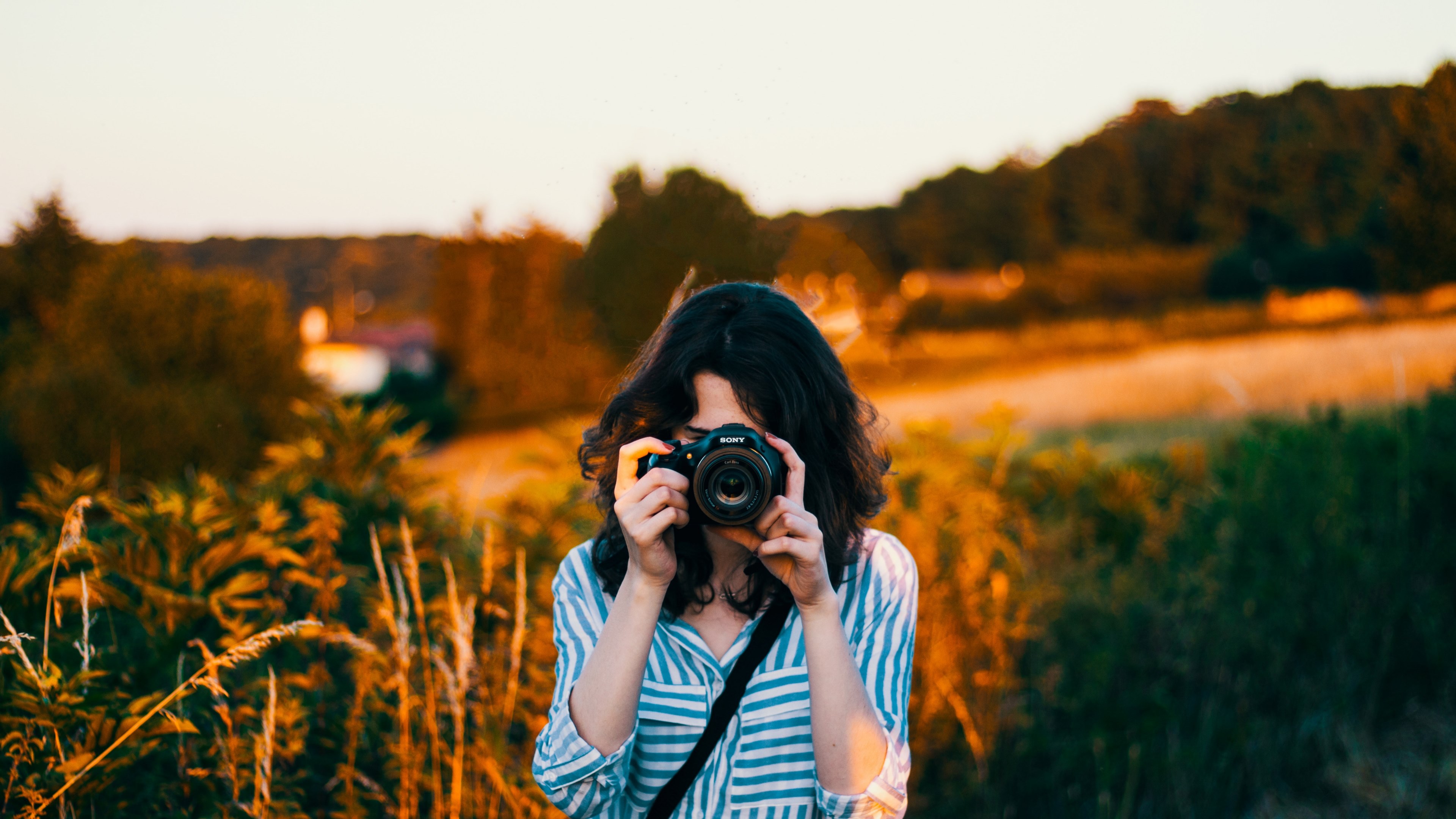 Wallpaper / photographer taking a picture with a sony camera in a country field, the field shooting 4k wallpaper free download