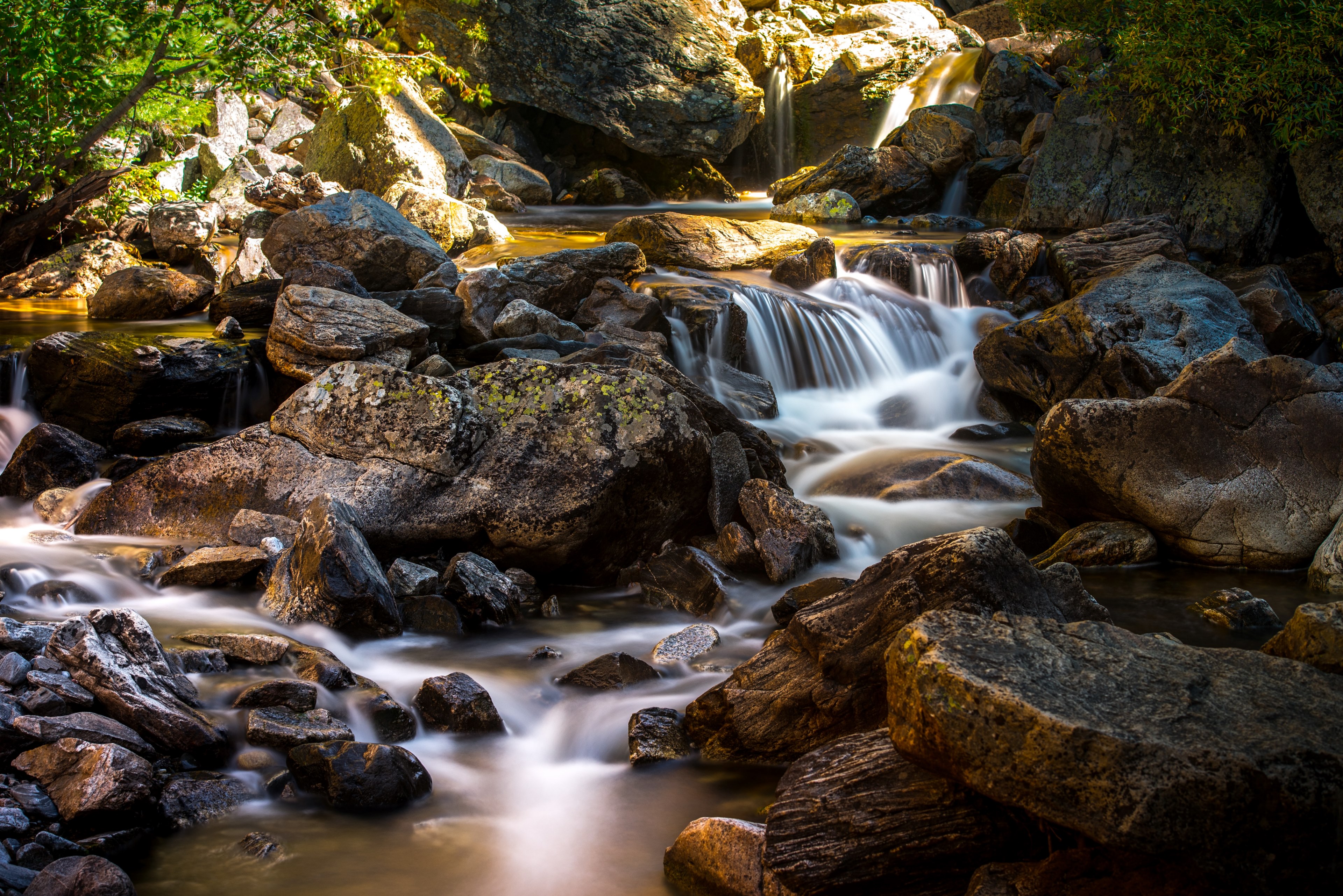 Wallpaper / a stream flowing through rocks in a creek at the bottom of a stony mountain, stony mountain river stream 4k wallpaper free download