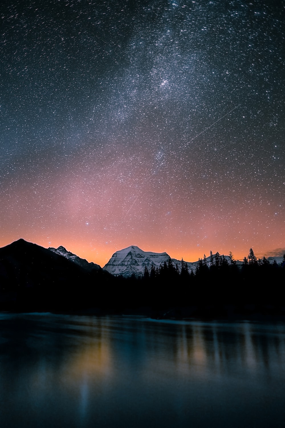 Lake surrounded by trees and mountain under milky way photo