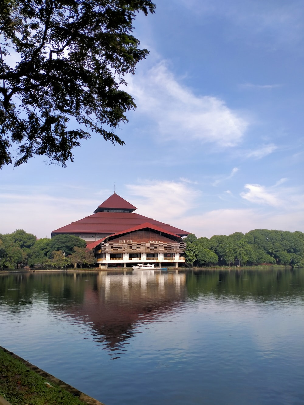 Brown wooden house on lake near green trees under blue sky during daytime photo