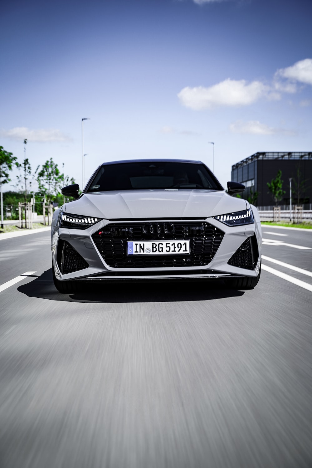 A white car driving down a street next to a building photo