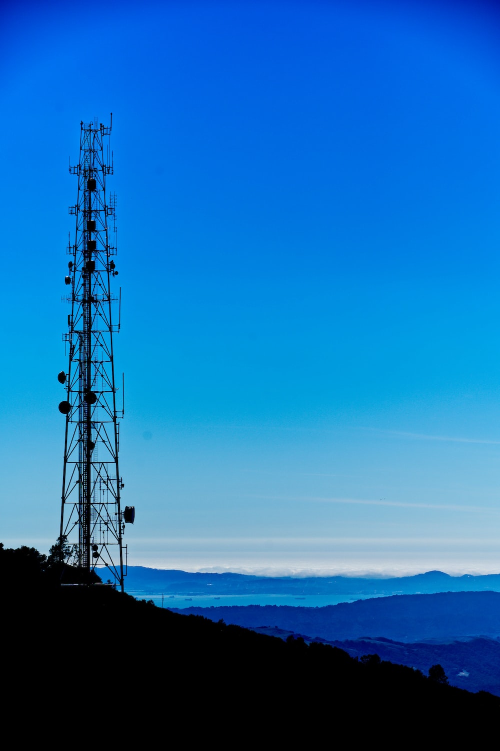 A radio tower on a hill with a blue sky in the background photo
