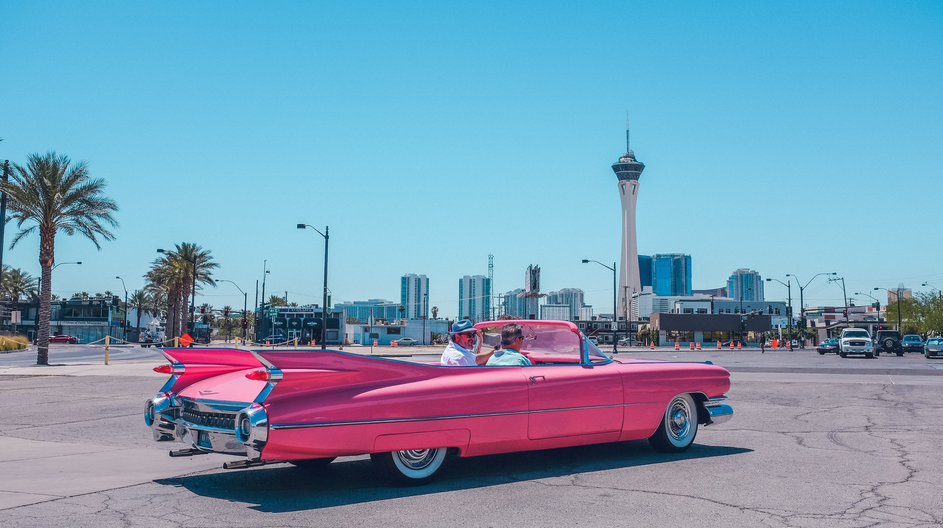 Wallpaper / pink vintage cadillac car on pavement on clear day in arts district with tower on skyline, vintage pink car 4k Wallpaper