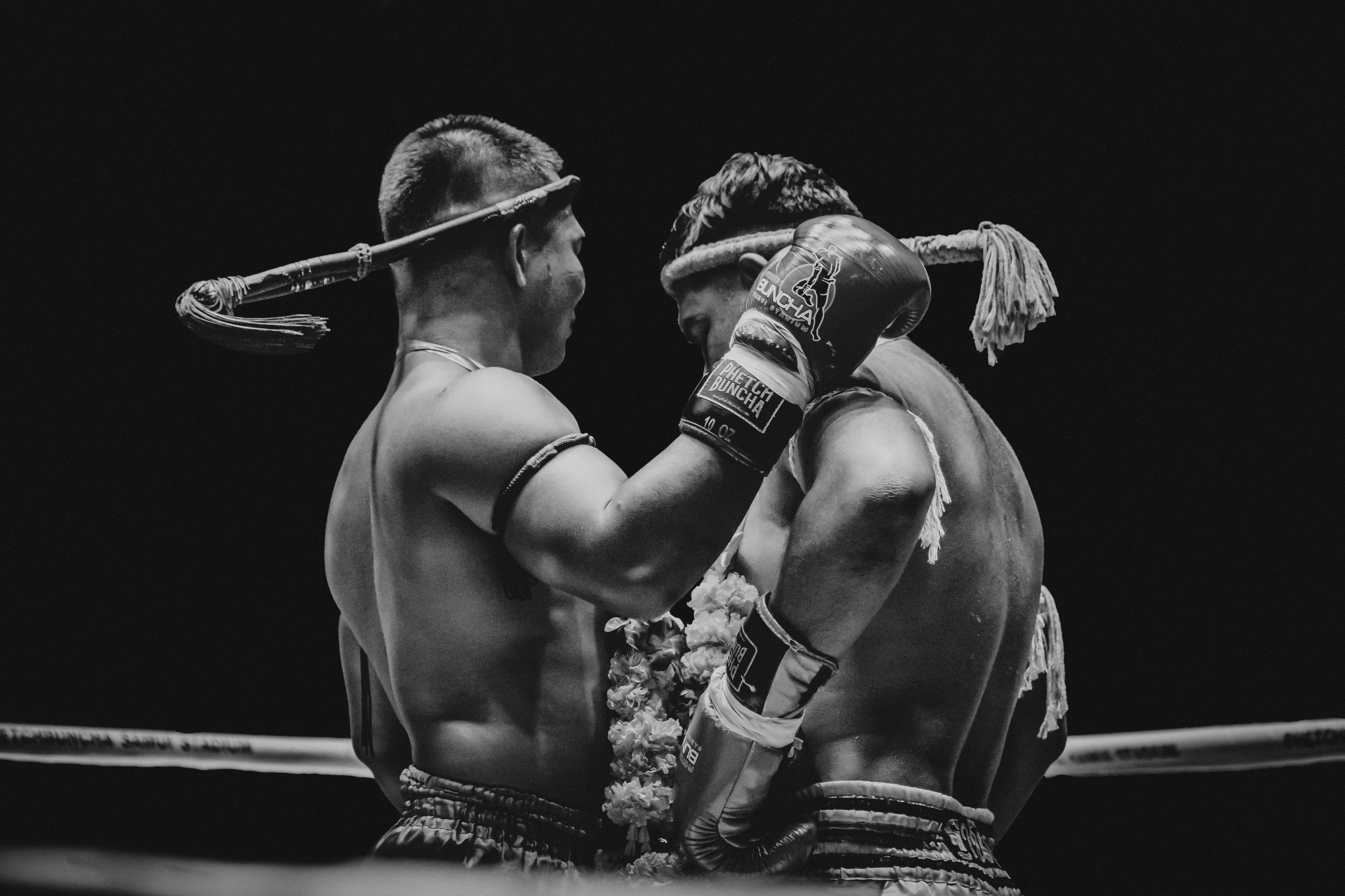 Grayscale Photography of Man Holding Boxer's Hand Inside Battle Ring · Free
