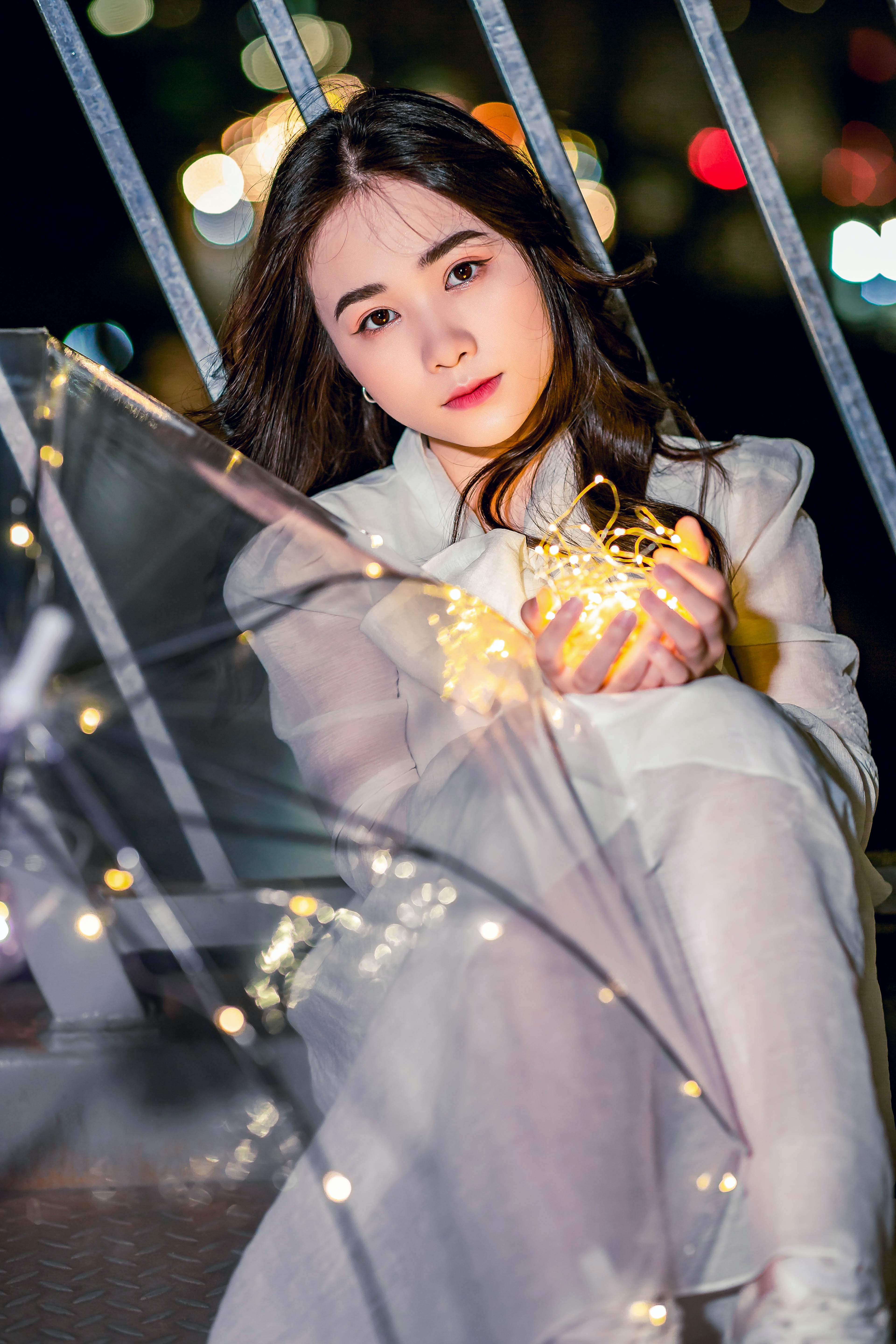 Photo of a Beautiful Woman in a White Dress Holding String Lights · Free