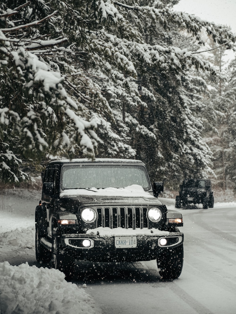 Black jeep wrangler on snow covered road during daytime photo