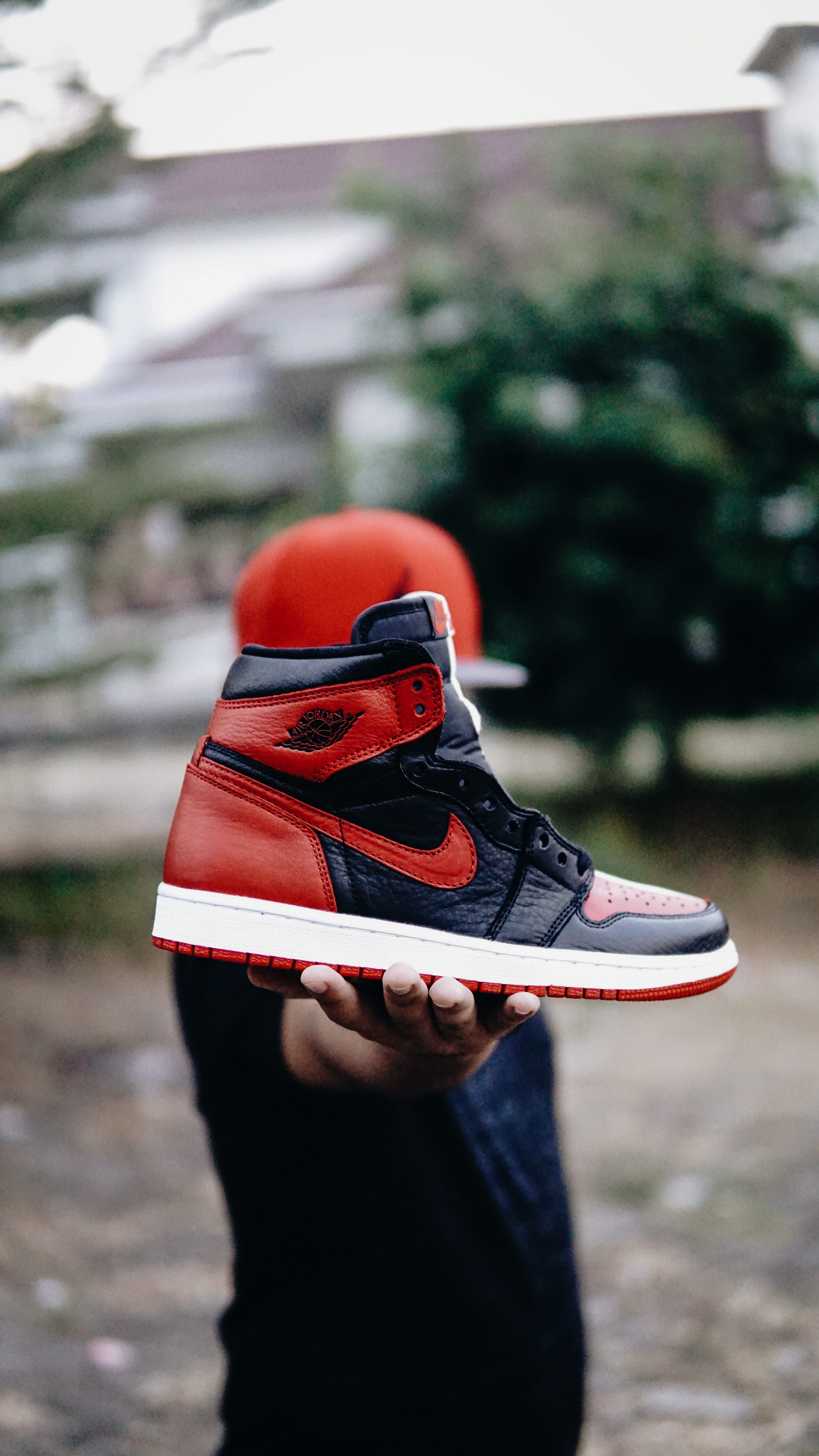 Wallpaper selective focus photo of person holding unpaired black and red Nike Air Jordan 1 shoe. Sneakers men fashion, Nike shoes roshe, Nike shoes (men)