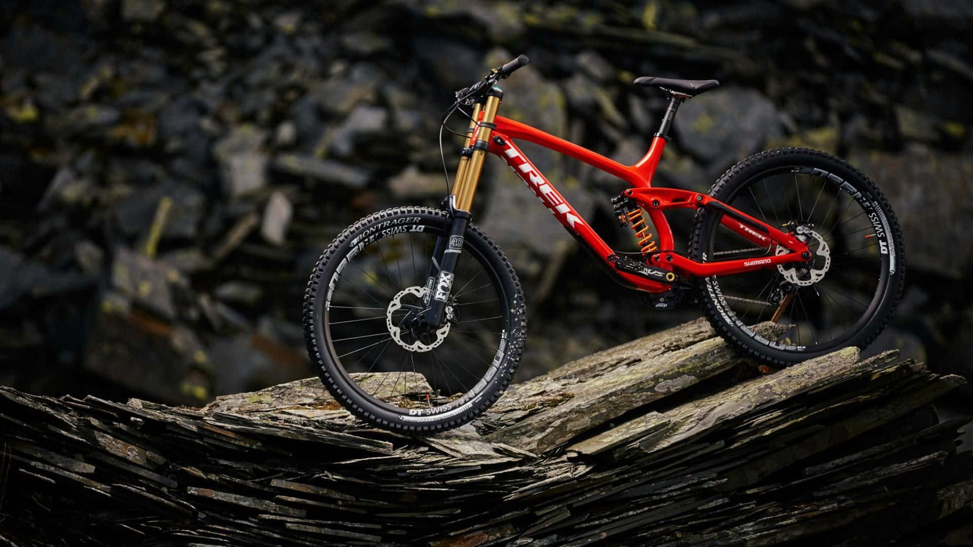 Download A Red Mountain Bike Is Sitting On Top Of Rocks Wallpaper