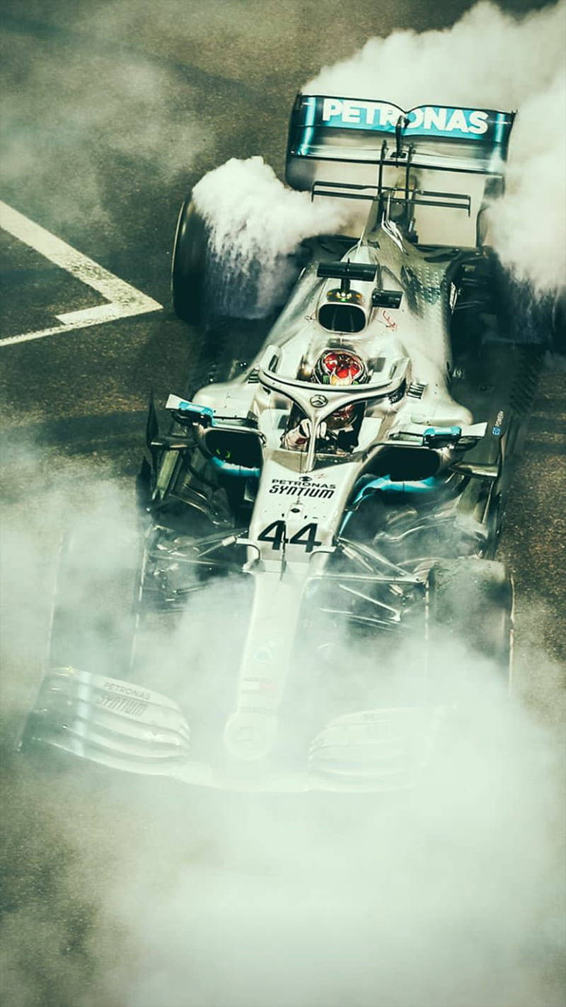 Download Race Car Of Lewis Hamilton F1 Covered With Smoke Wallpaper