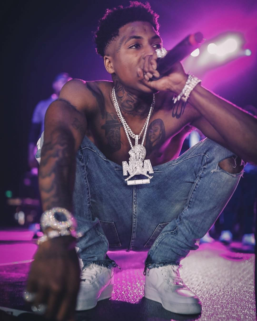 Download NBA Youngboy appearing on purple neon lights stage Wallpaper