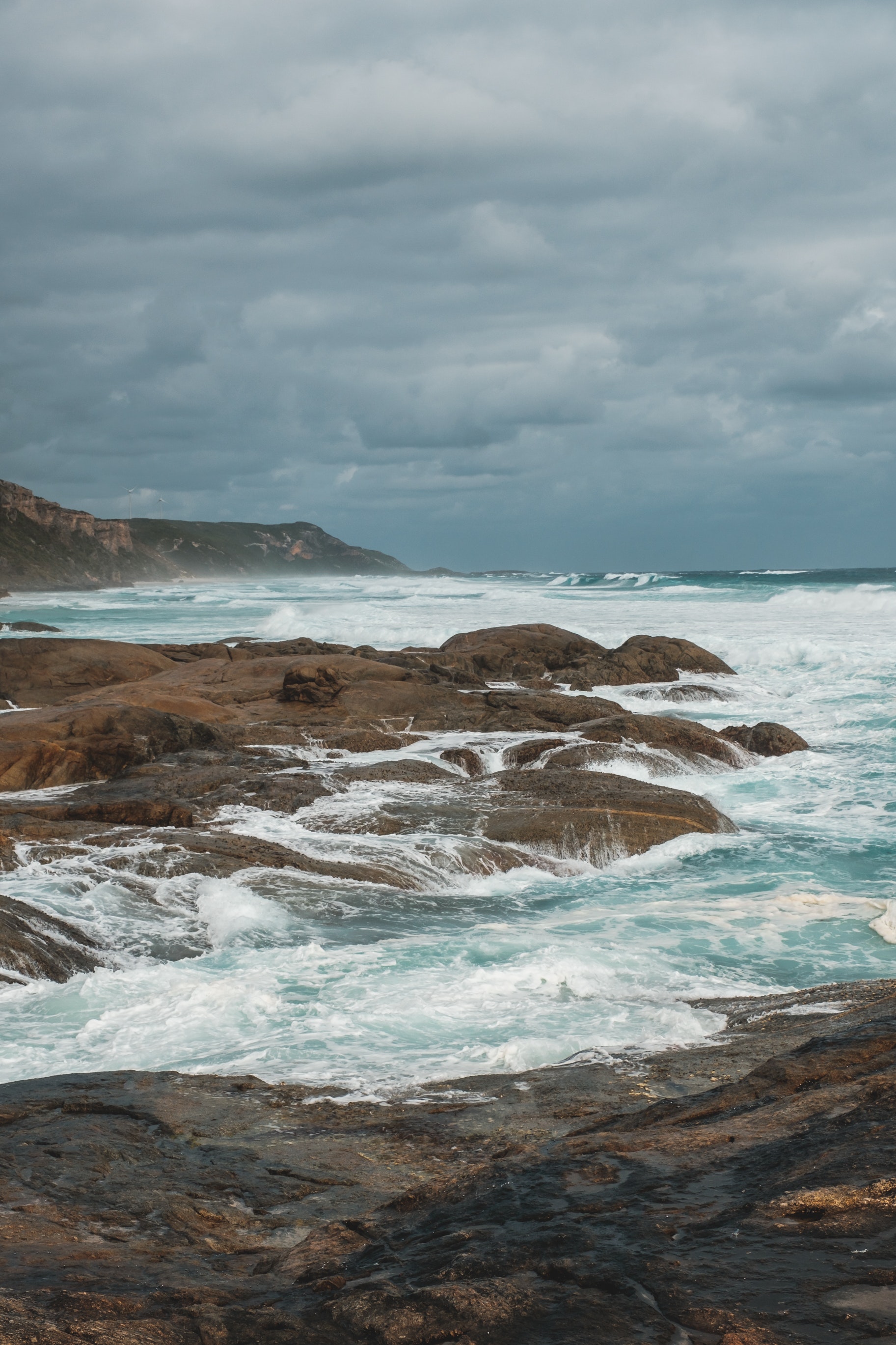 Rocky cliff washed by stormy sea on gloomy weather · Free