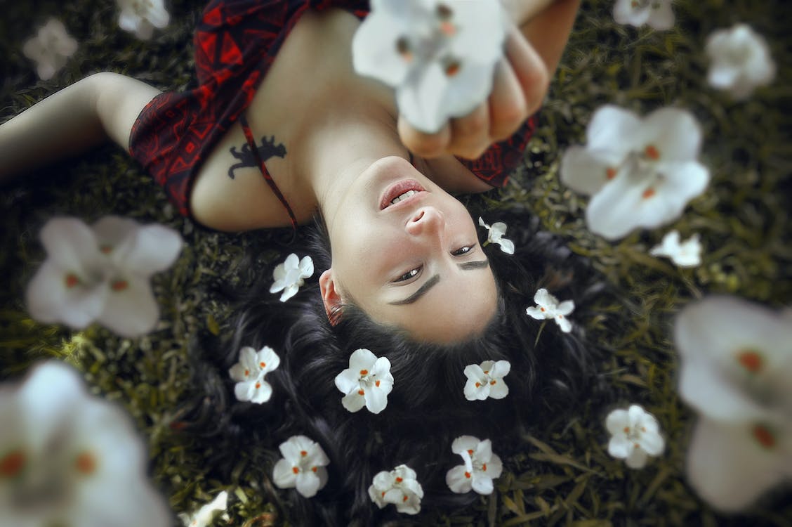 A Woman Lying on the Grass Surrounded with Flowers · Free