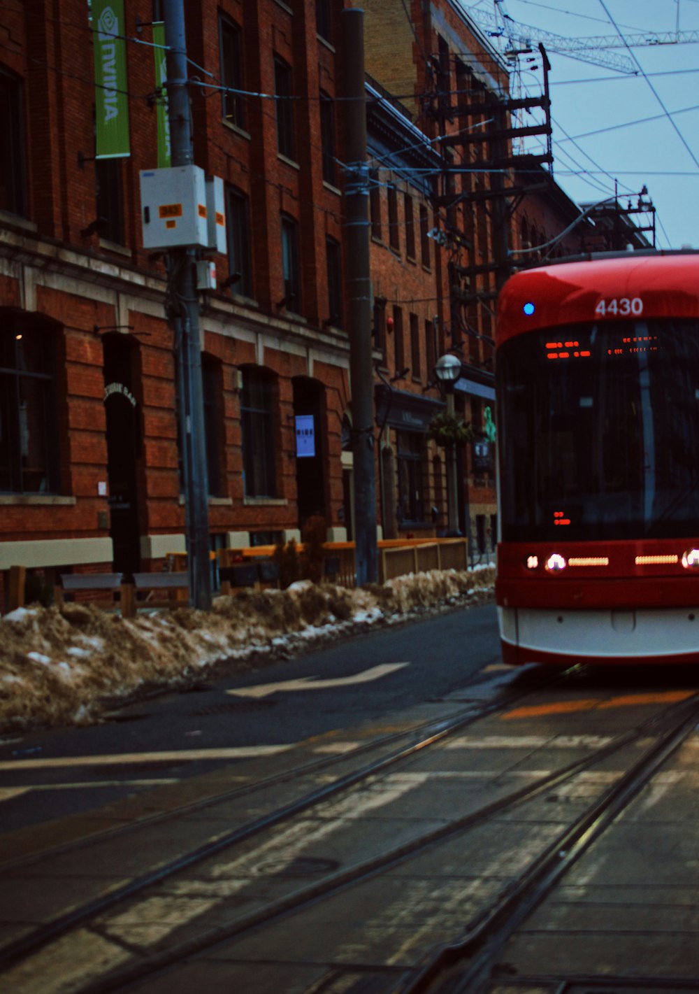 A red and white train traveling down a street next to tall buildings photo