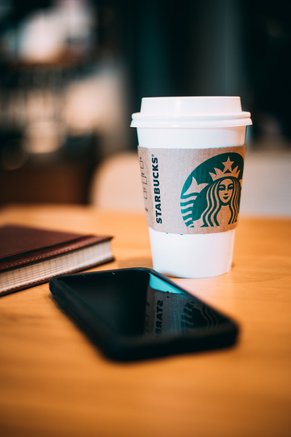 Black smartphone beside a white Starbucks cup photo