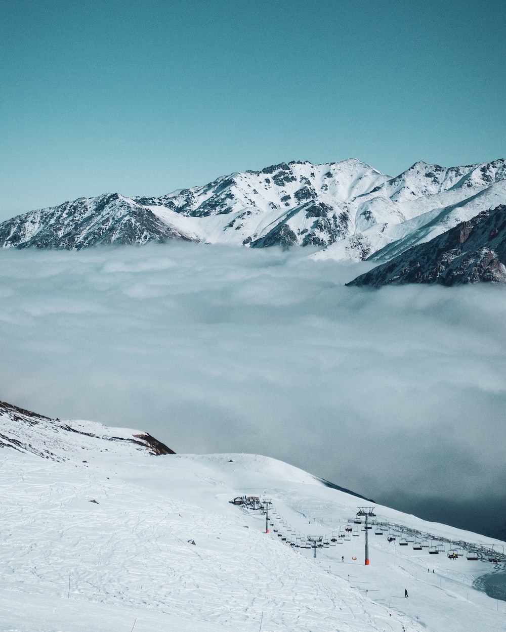 A snowy mountain with a ski lift in the foreground photo