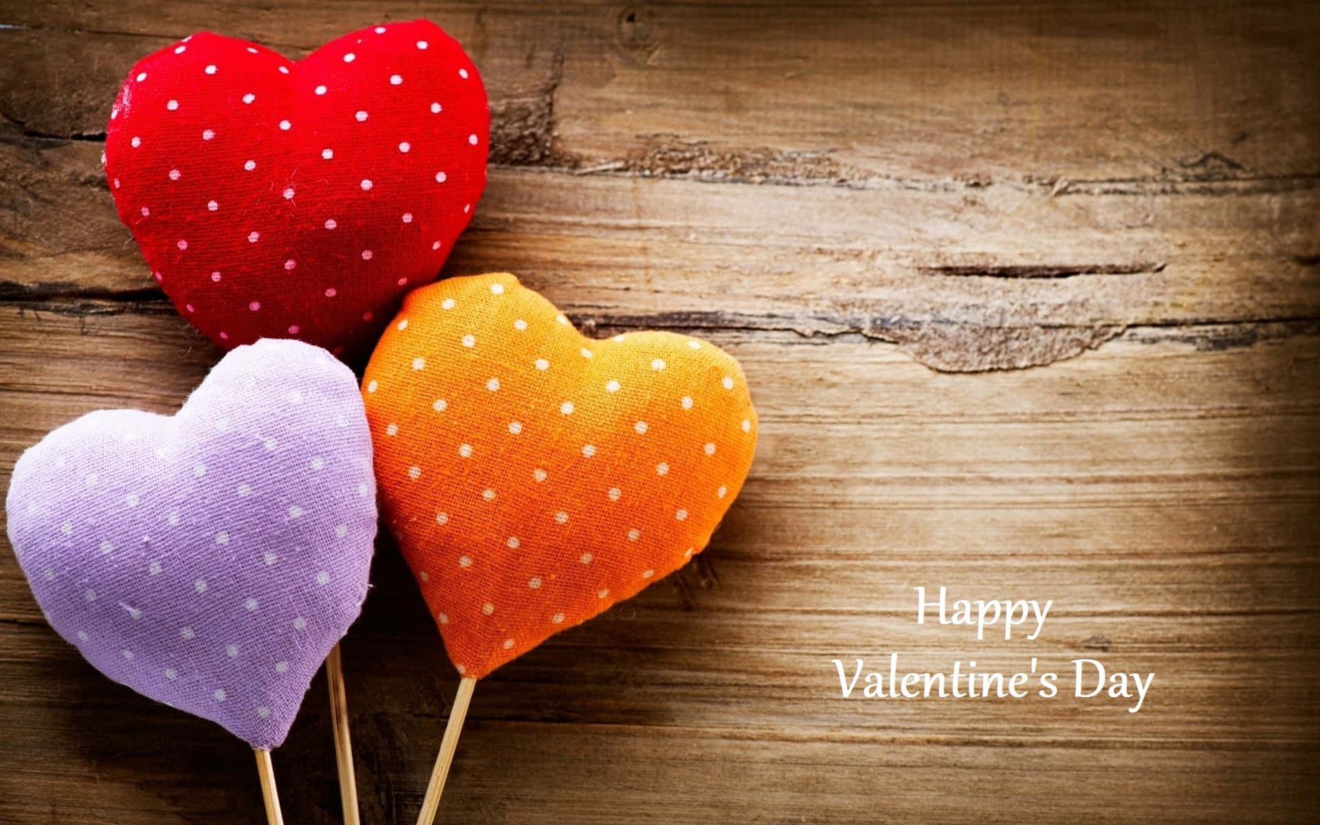 Download Three Colorful Heart Shaped Stuffed Toys On A Wooden Background