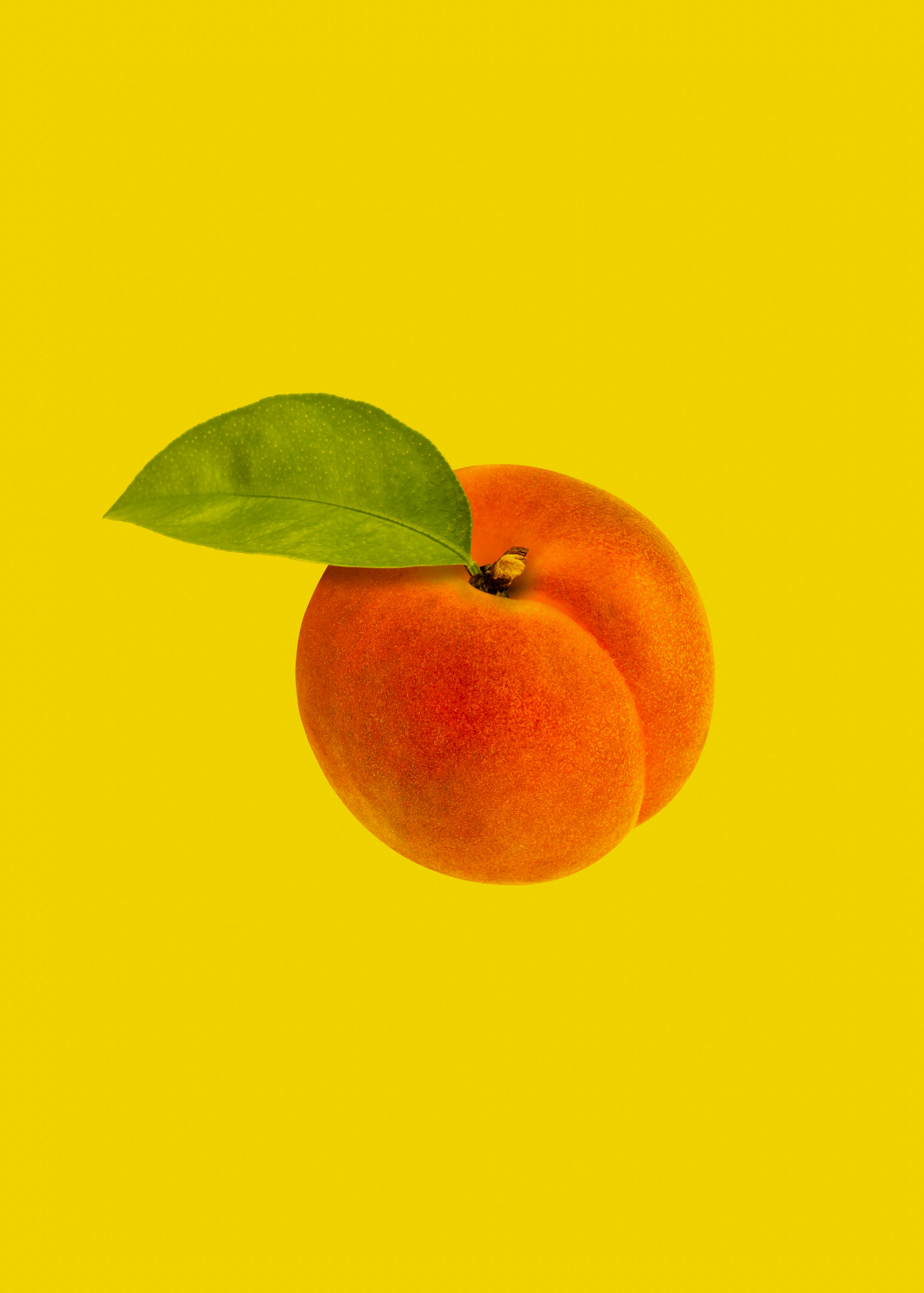 Studio Shot of Ripe Peach on Yellow Background · Free