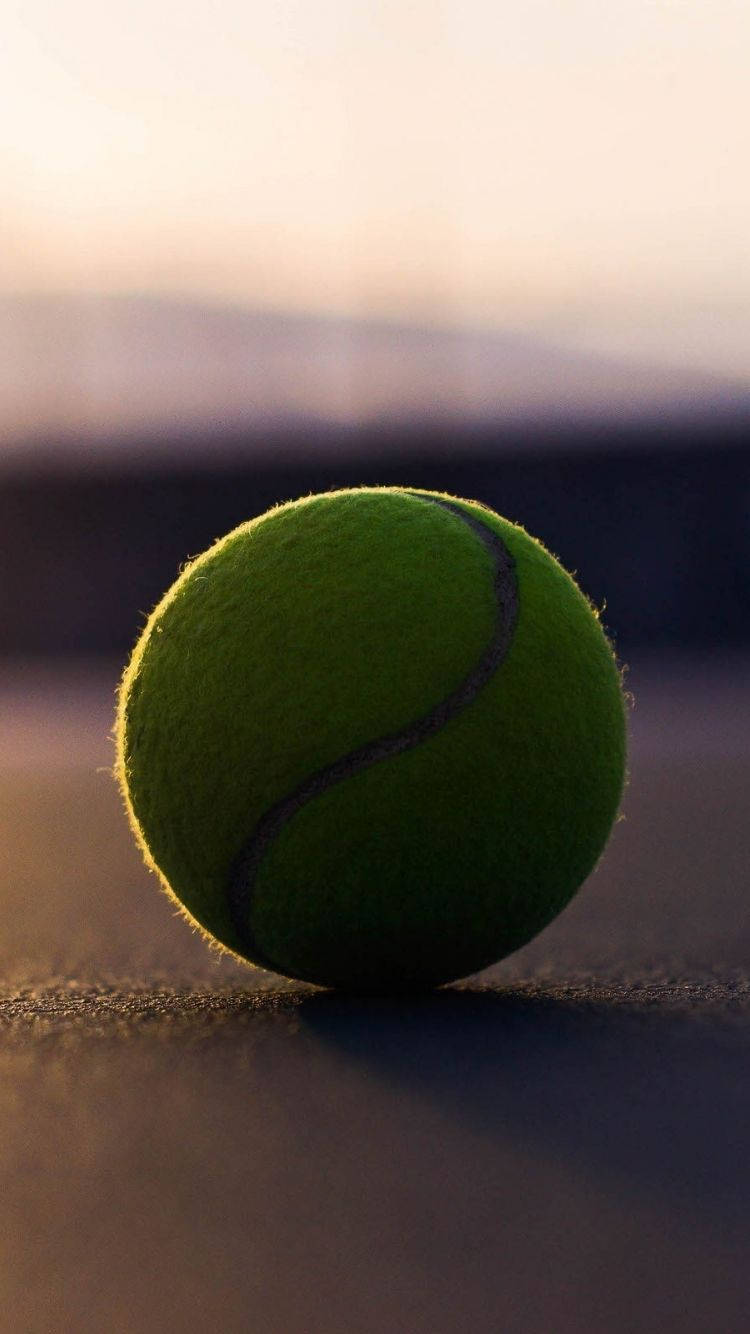 Download A Tennis Ball On A Tennis Court Wallpaper
