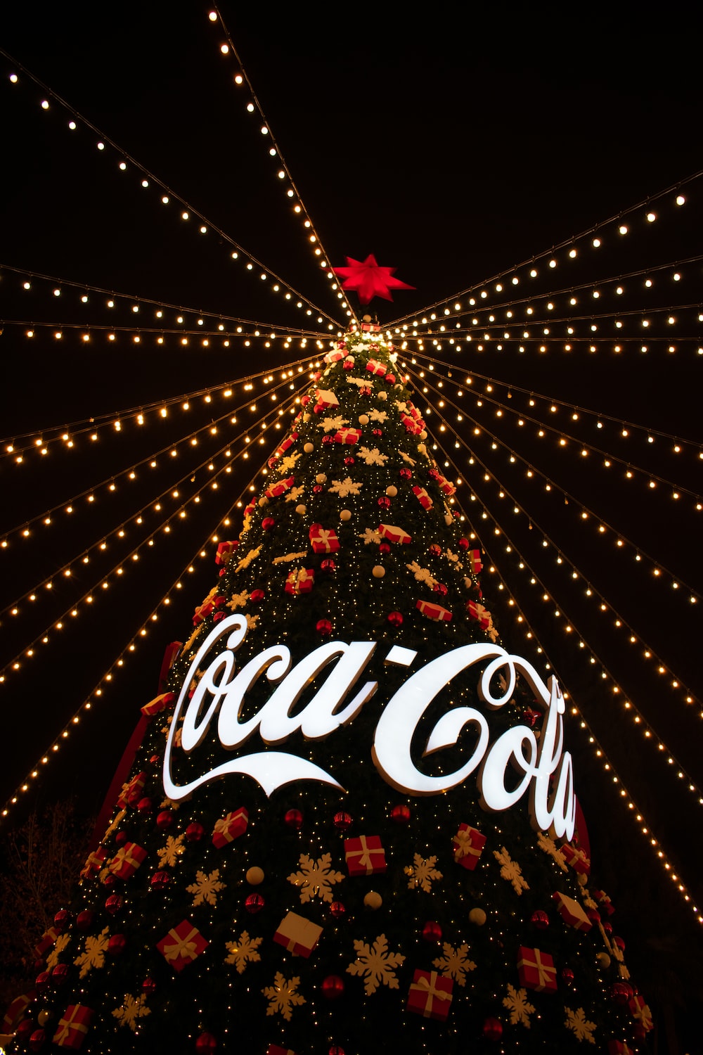 A coca cola christmas tree is lit up at night photo
