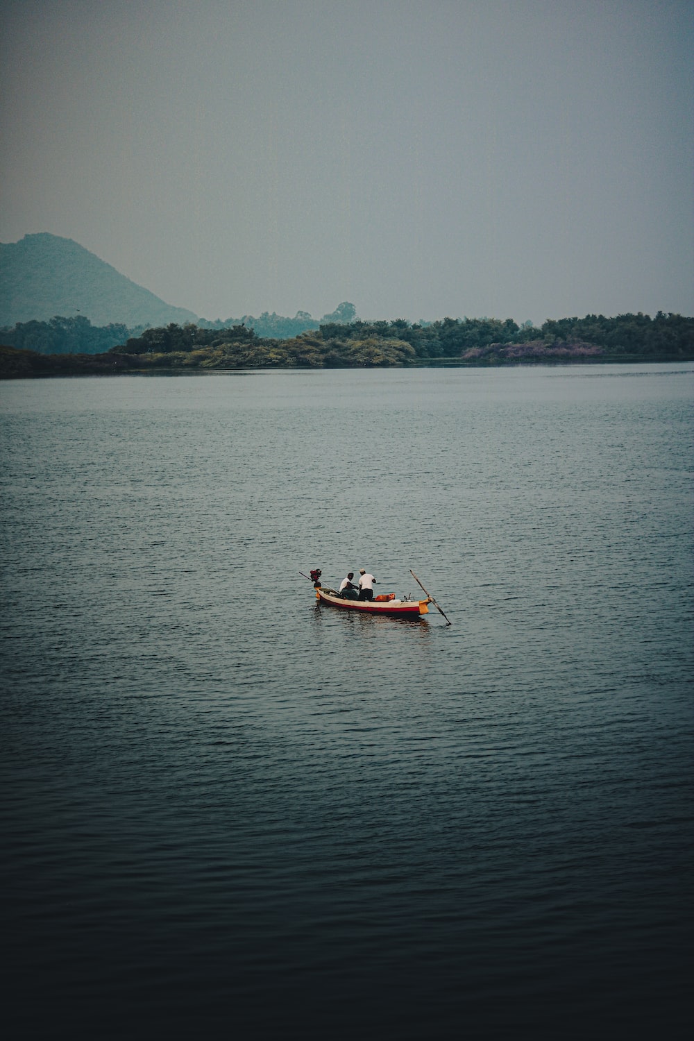 A small boat floating on top of a large body of water photo