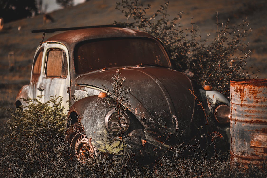 Photo of Abandoned Vintage Volkswagen Beetle Near Rusty Drum · Free