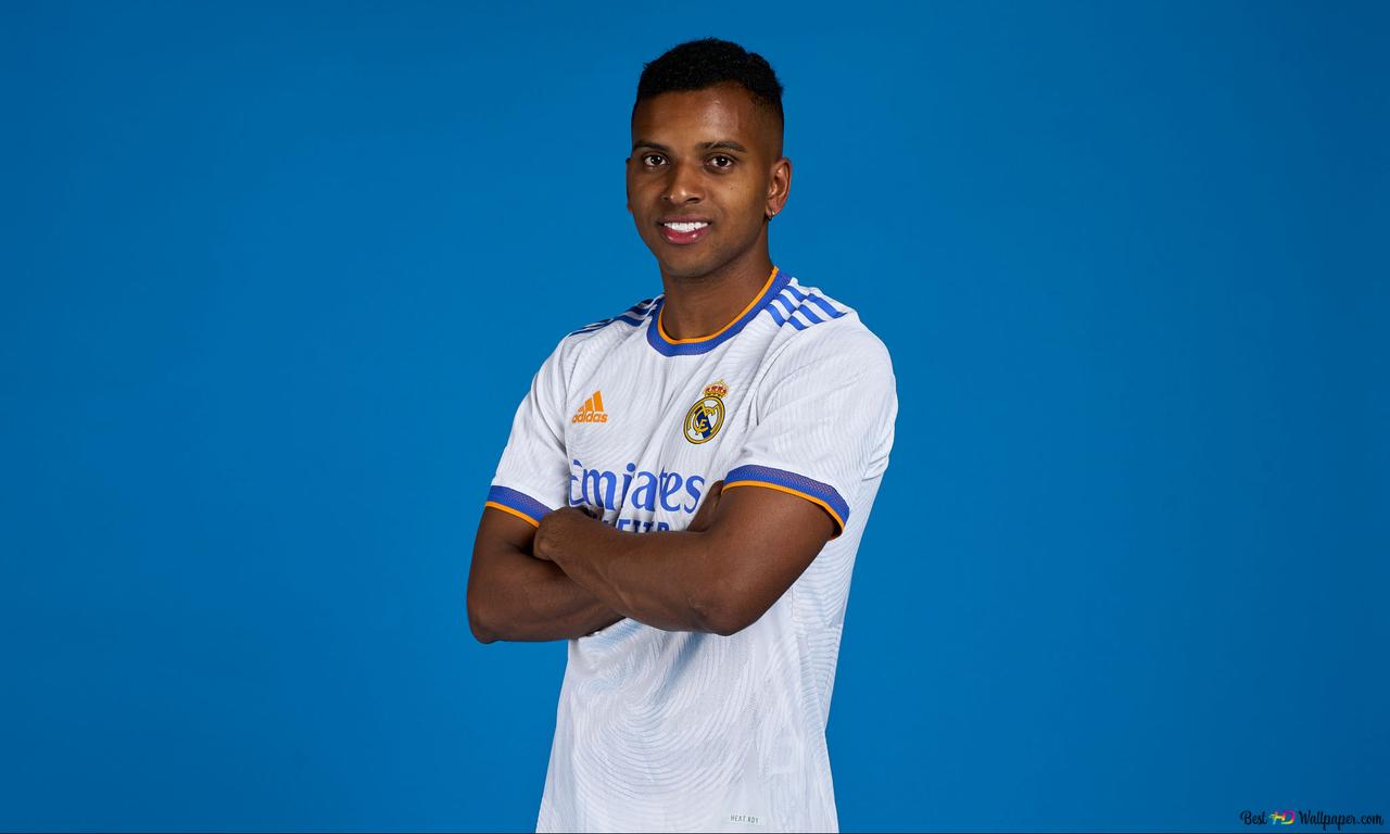 Rodrygo poses with clasped hands in front of a blue background, dressed in the jersey of Rebellion La Liga strong team Real Madrid 2K wallpaper download