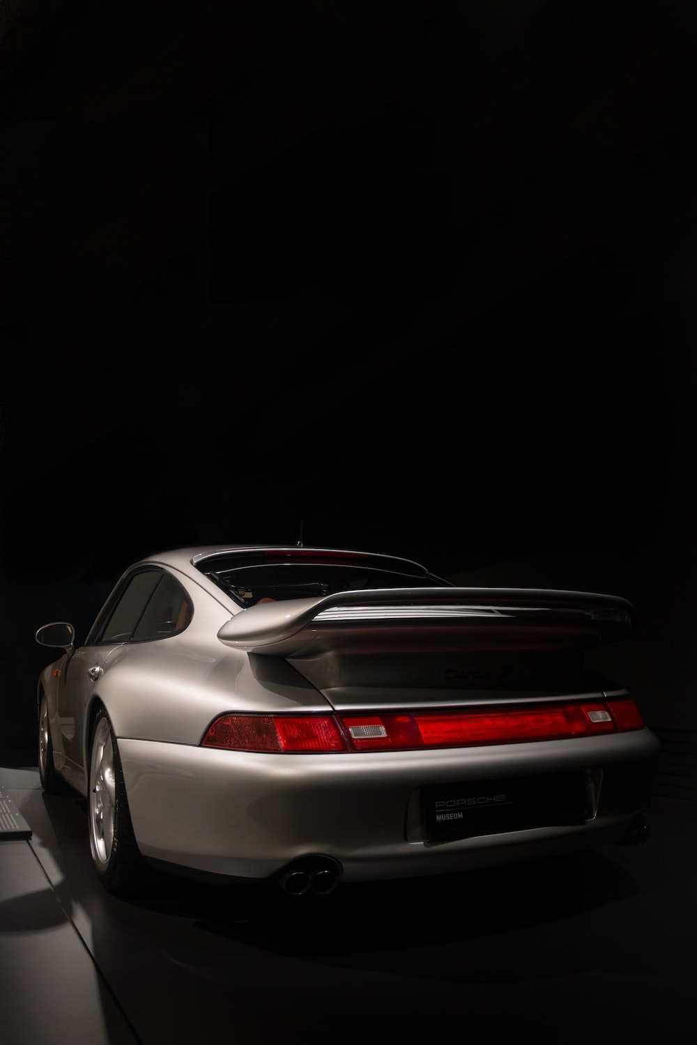 A white porsche parked in a dark room photo