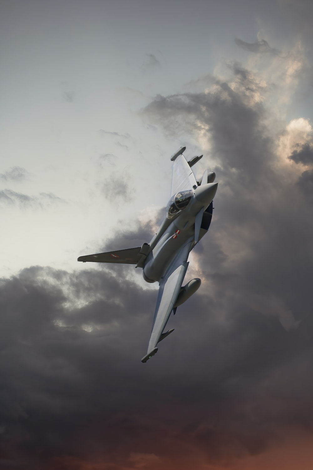 fighter jet flying through a cloudy sky