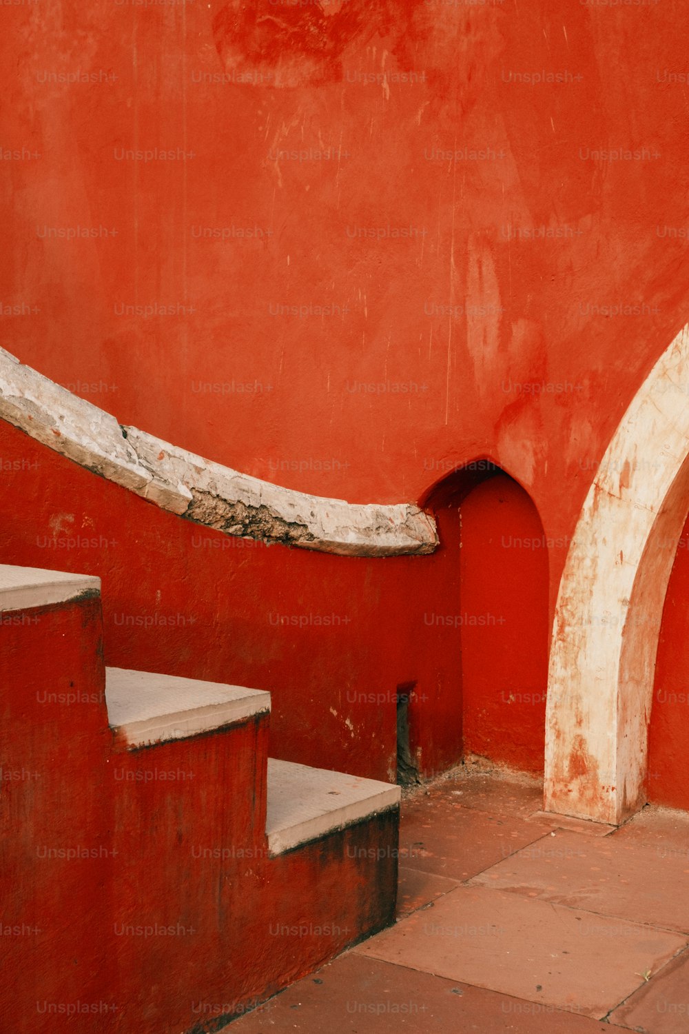 A red wall with a white arch next to it