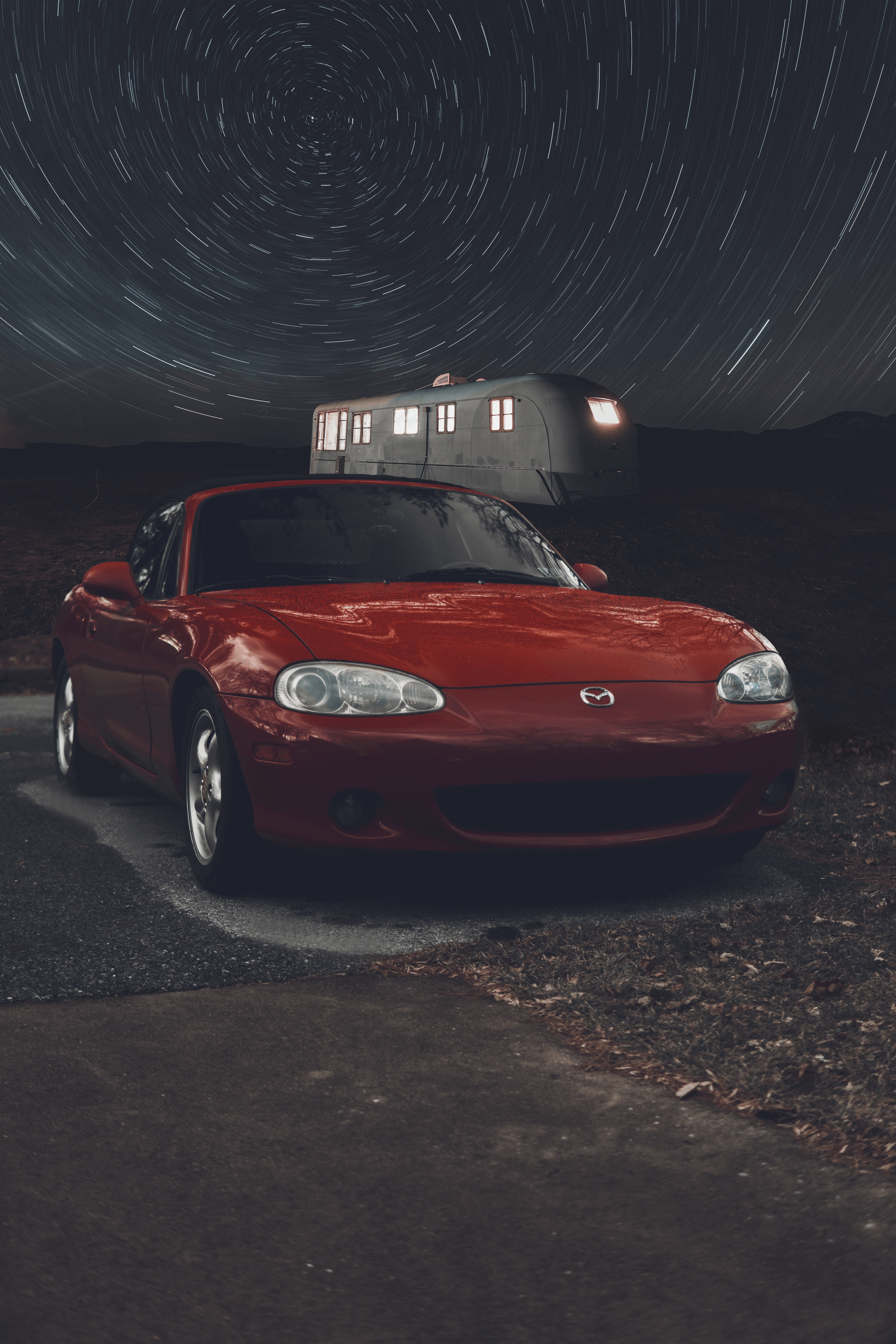 Red Sports Car Parked Near a Camper