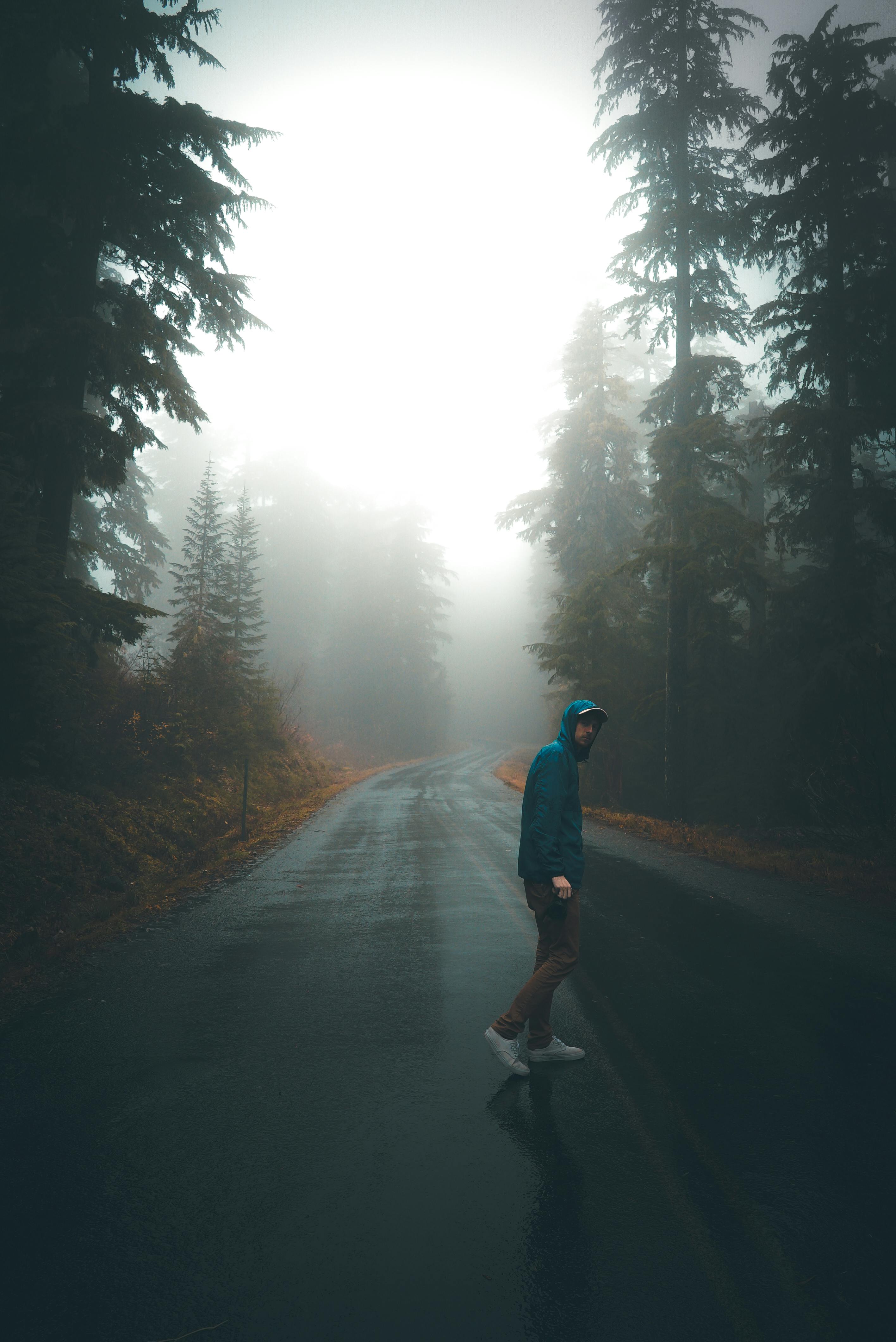 Man crossing lonely road in misty woods
